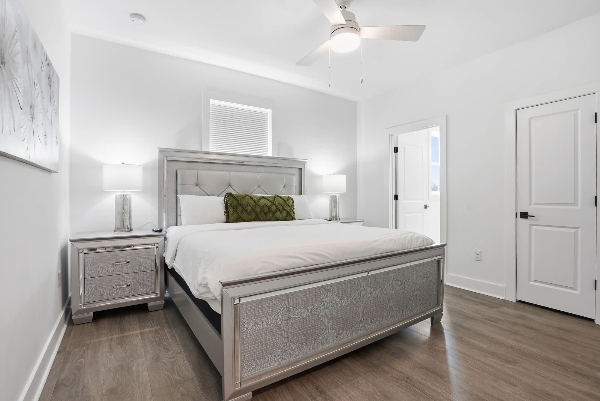 120 Dune Drive – Bright bedroom with a large bed, nightstands, and modern decor, featuring a ceiling fan and window.