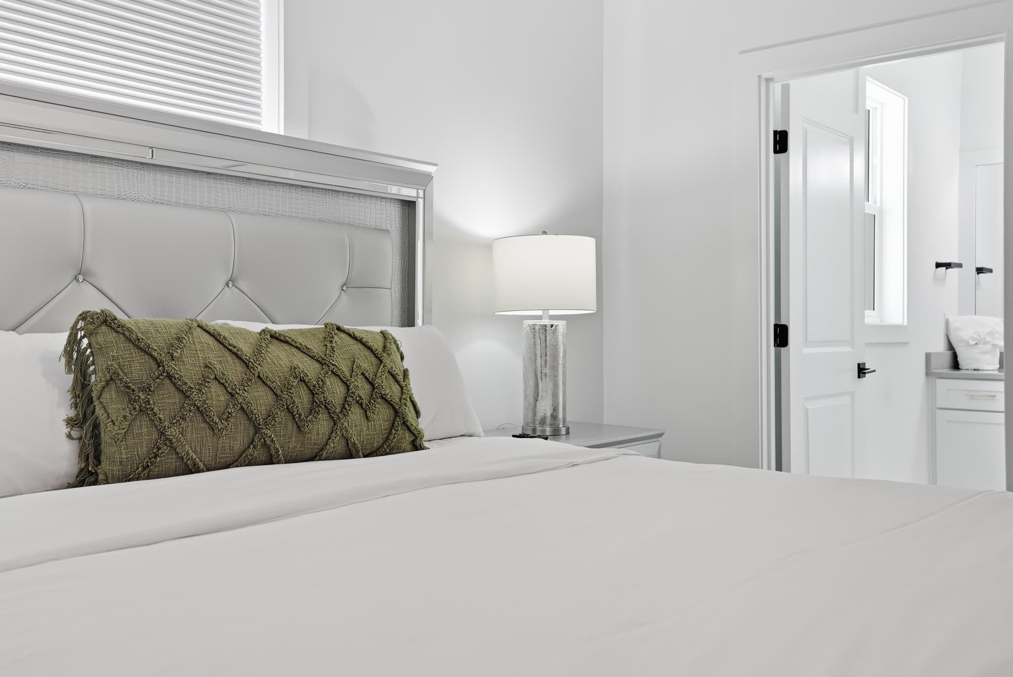 120 Dune Drive – Cozy bedroom featuring a plush bed, green accent pillow, lamp, and doorway to a bathroom area.