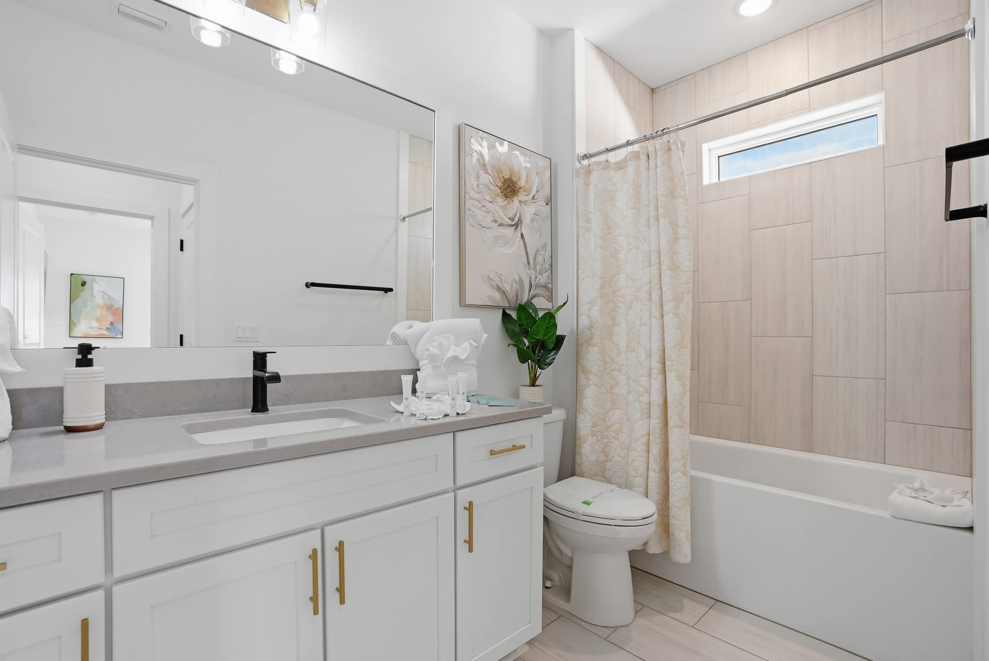 120 Dune Drive – Modern bathroom with gray countertop, white cabinetry, shower curtain, and decorative plant.