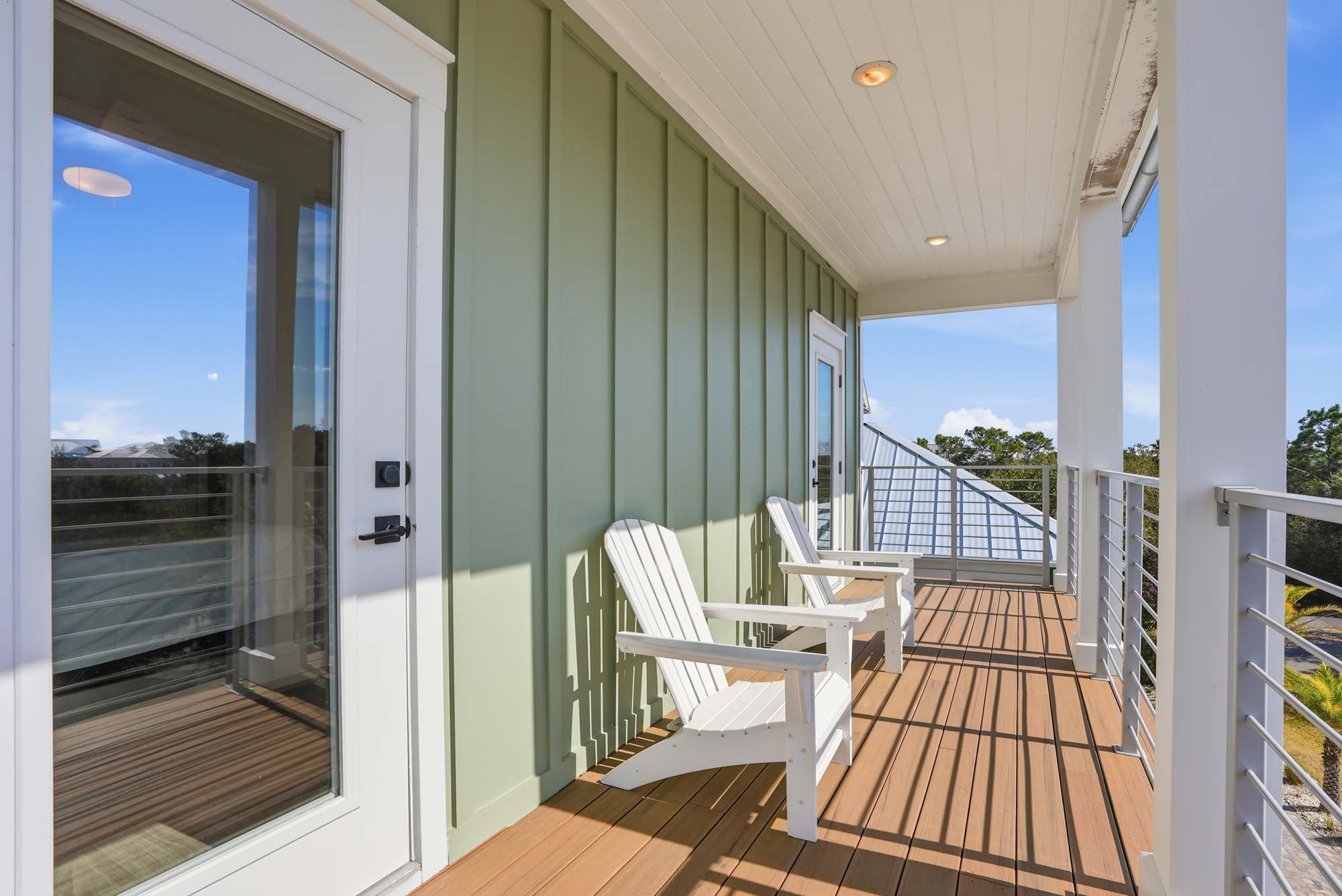 120 Dune Drive – Deck area with two white Adirondack chairs and a view of greenery.
