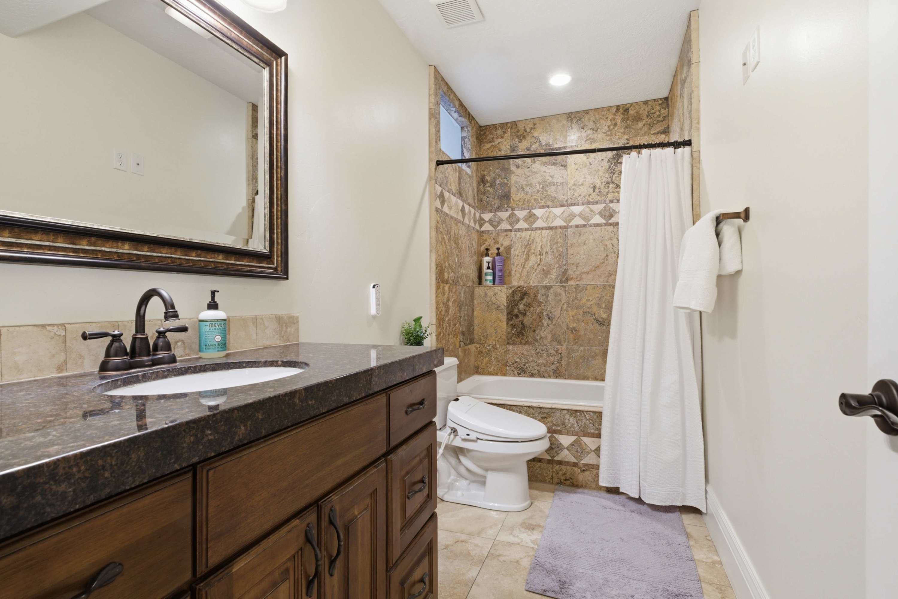 Spacious full bathroom with granite counters and tiled shower