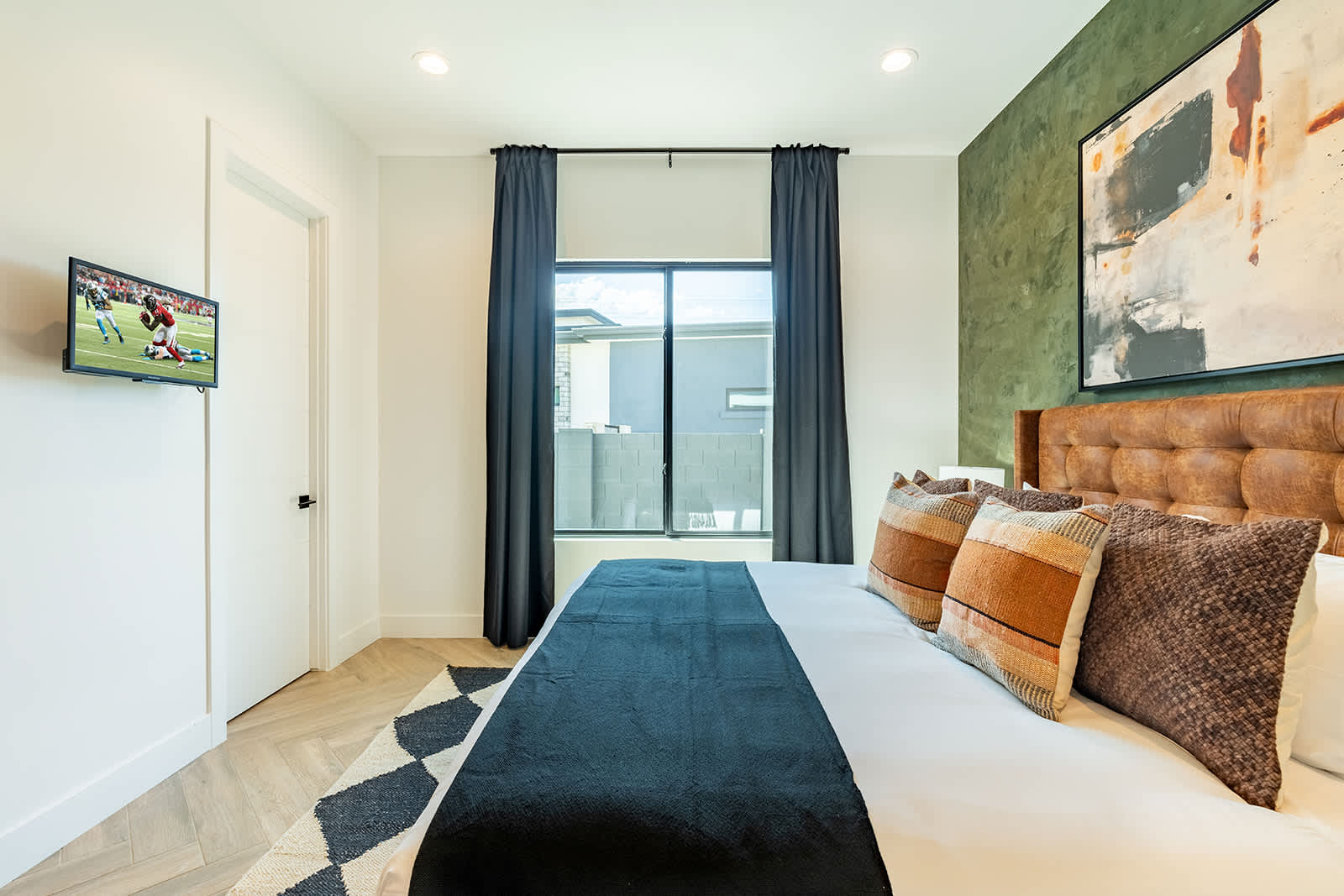 2nd bedroom with a King bed, smart TV, walk-in closet, custom accent wall, and an en-suite bathroom.