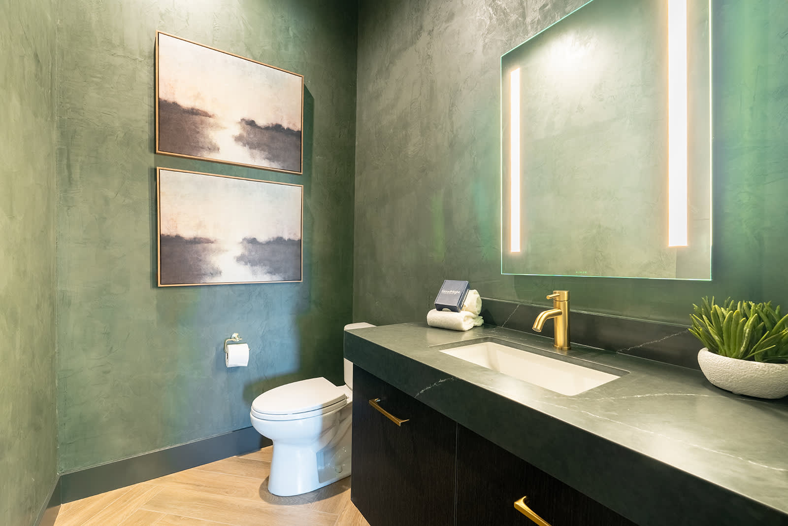 The 5th bathroom is a half bathroom found in the hallway hosting a single vanity with built-in LED lighting.
