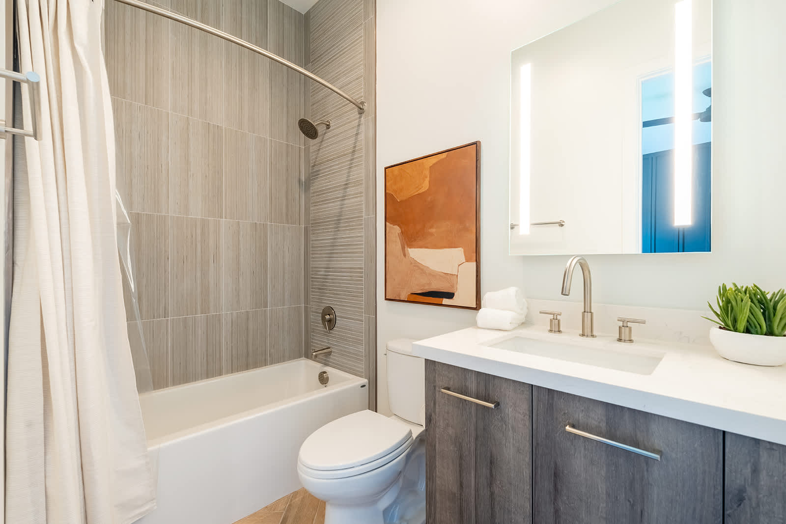 3rd en-suite bathroom with a shower/tub combo and single vanity containing LED lighting.