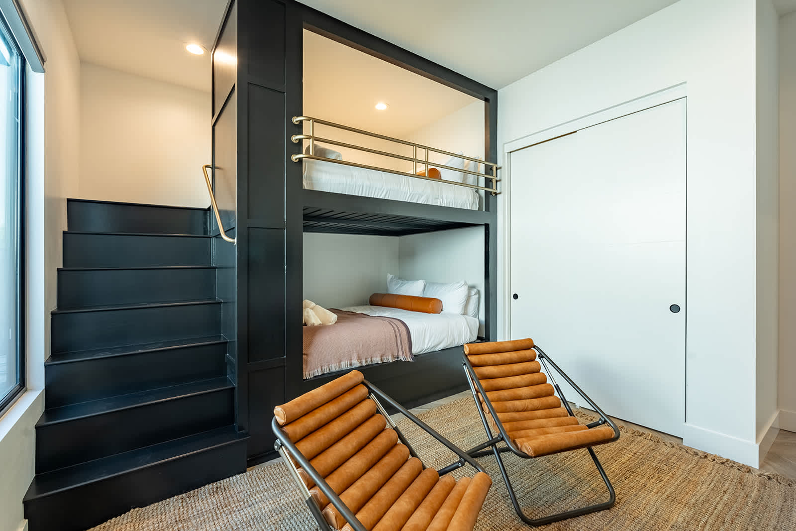 5th bedroom offering an accommodating layout featuring 2 full sized beds (bunk-style), closet space, smart TV, accent wall, and designer furnishings.