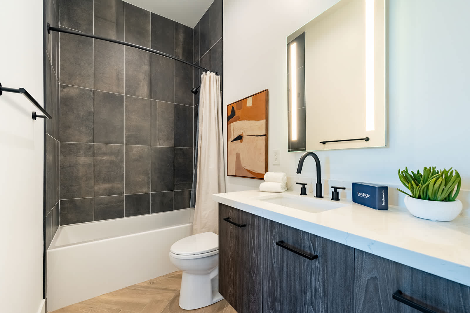 4th en-suite bathroom in a jack and jill layout with a shower/tub combo and single vanity with built-in LED lights.
