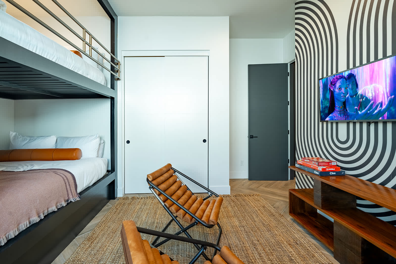 5th bedroom offering an accommodating layout featuring 2 full sized beds (bunk-style), closet space, smart TV, accent wall, and designer furnishings.