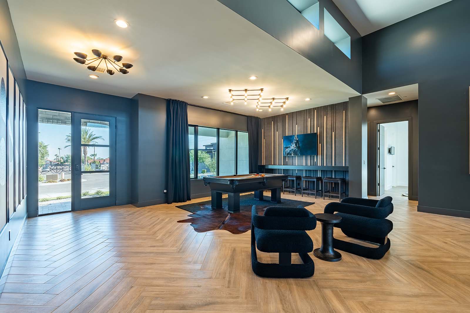 Stylish entertainment space featuring a sleek pool table, modern lighting, and a cozy seating area with a large Smart TV.