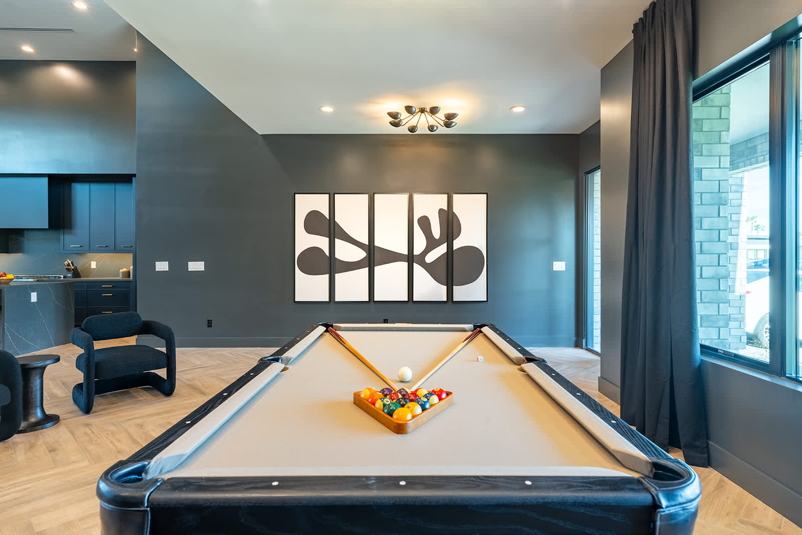 Stylish entertainment space featuring a sleek pool table, modern lighting, and a cozy seating area with a large Smart TV.