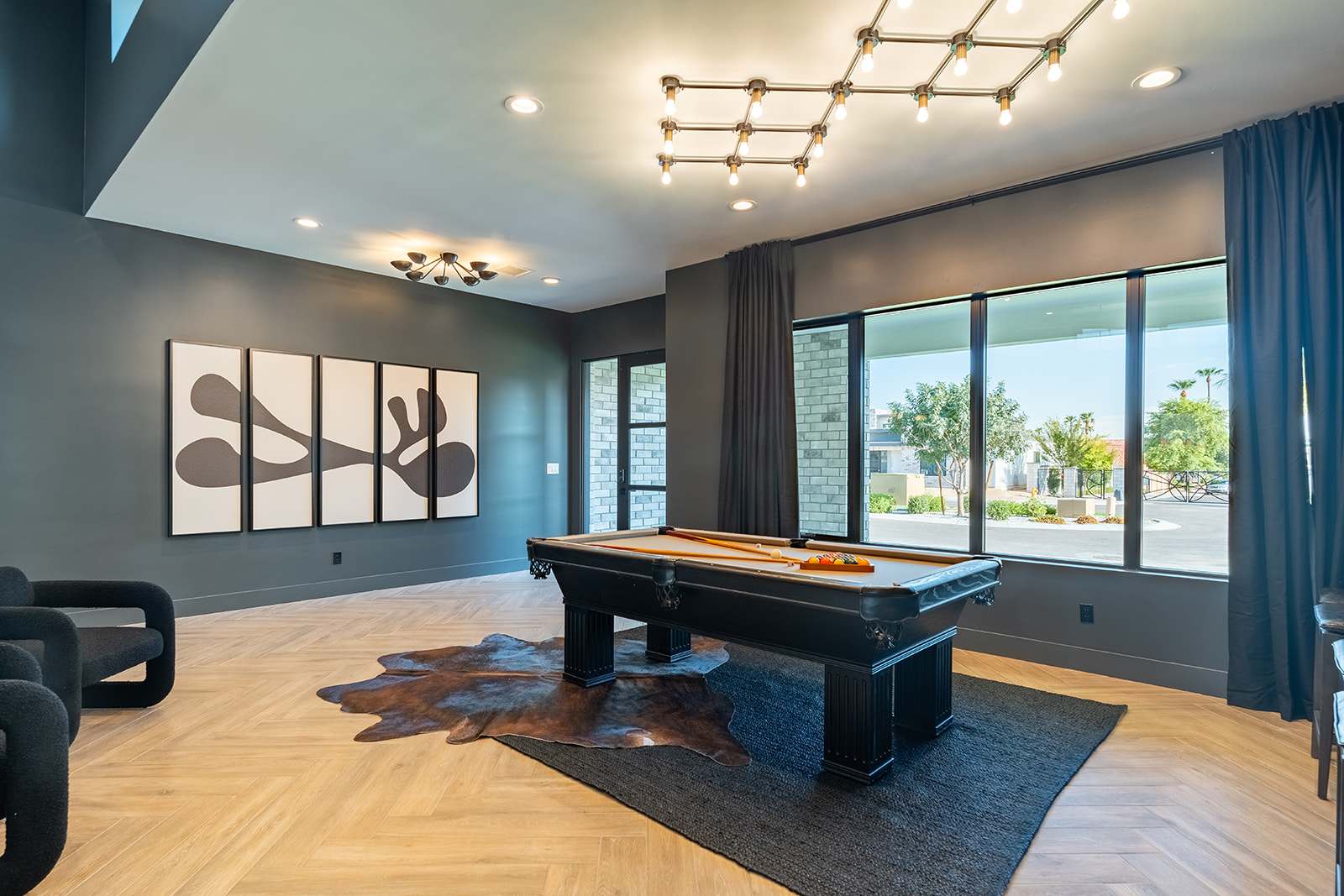 Stylish entertainment space featuring a sleek pool table, modern lighting, and a cozy seating area with a large Smart TV.