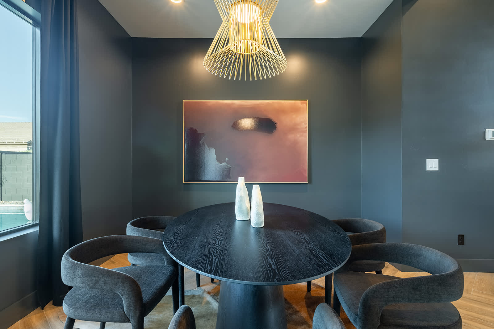 The modern dining area features a striking black wooden dinner table and seating for 6 in it's comfortable padded chairs.