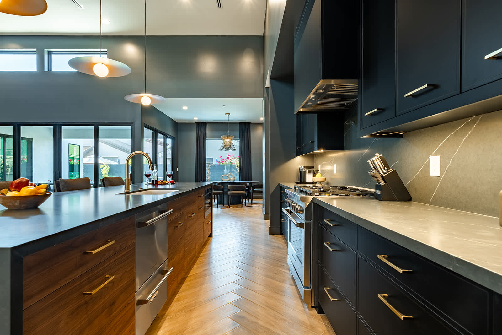 Gather in this sleek, modern kitchen featuring dark cabinetry, a spacious island with seating for four, and warm pendant lighting—perfect for casual meals or socializing.