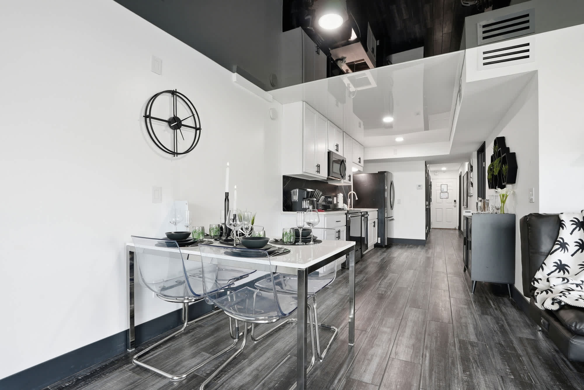 The Summit 132 – Modern kitchen and dining area with glass table, gray flooring, and stainless steel appliances.