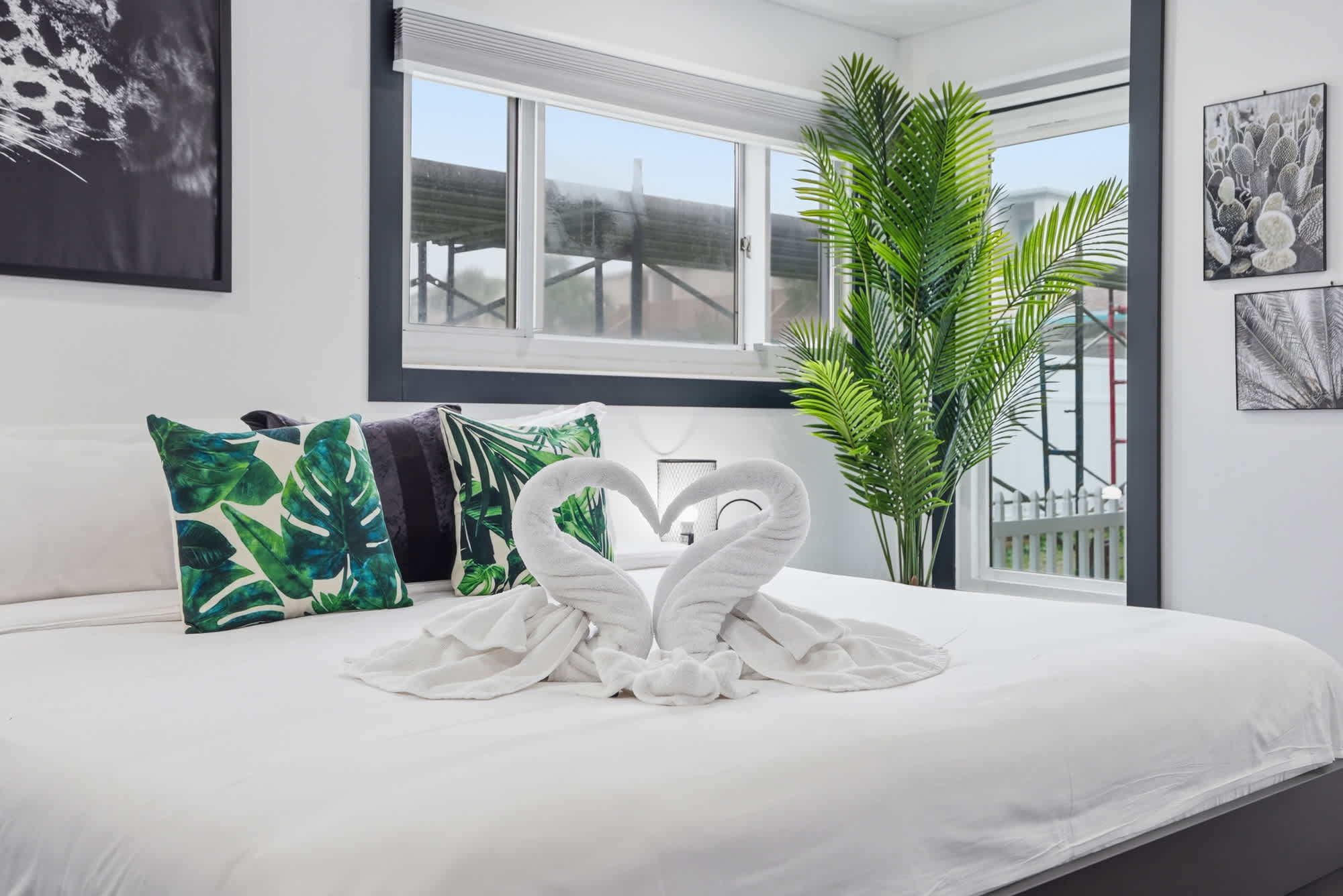 The Summit 132 – Stylish bedroom with a large bed, decorative pillows, towel swans, and a tropical plant by the window.