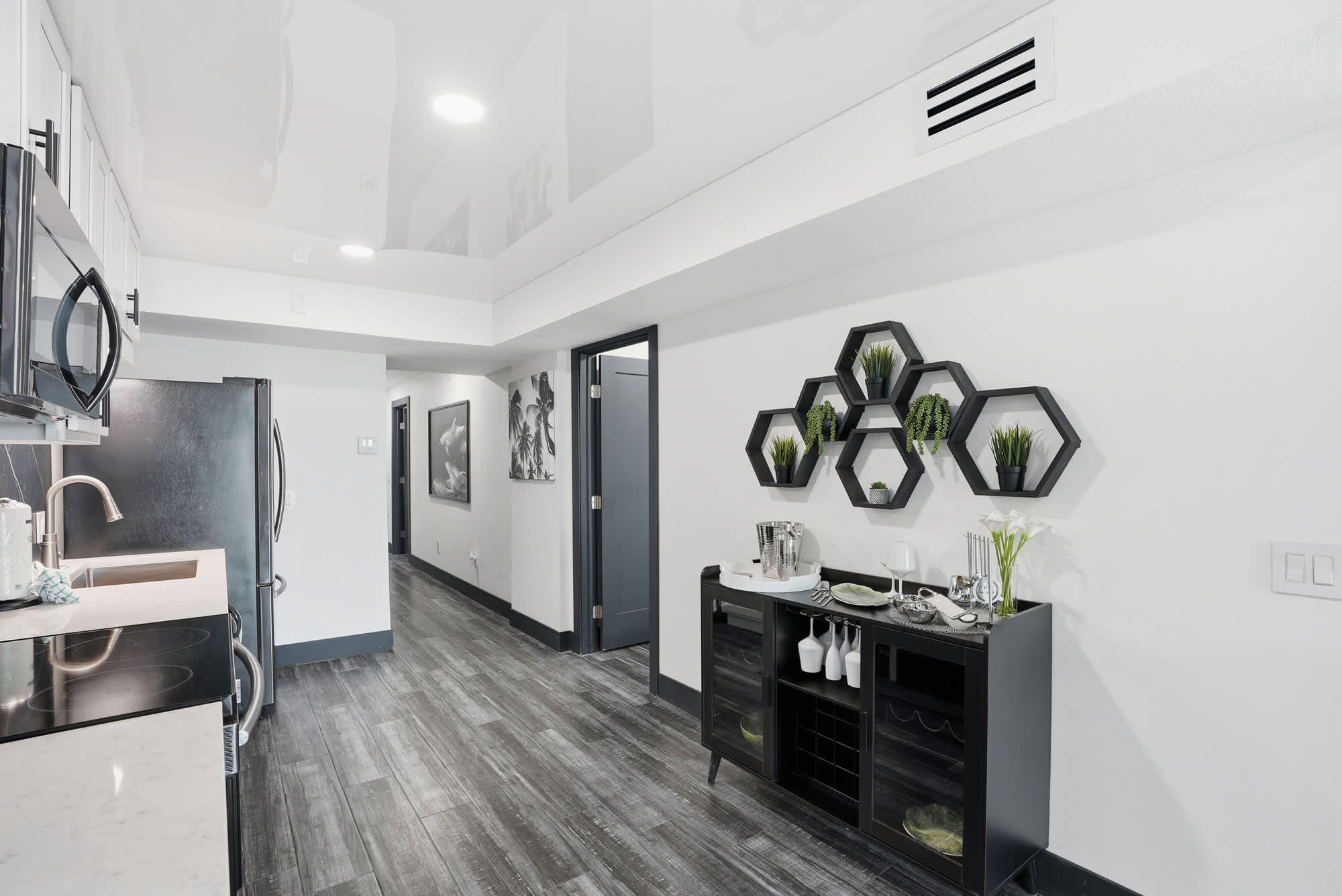 The Summit 132 – Modern kitchen area with dark cabinetry, hexagonal wall shelf, and a hallway leading to other rooms.