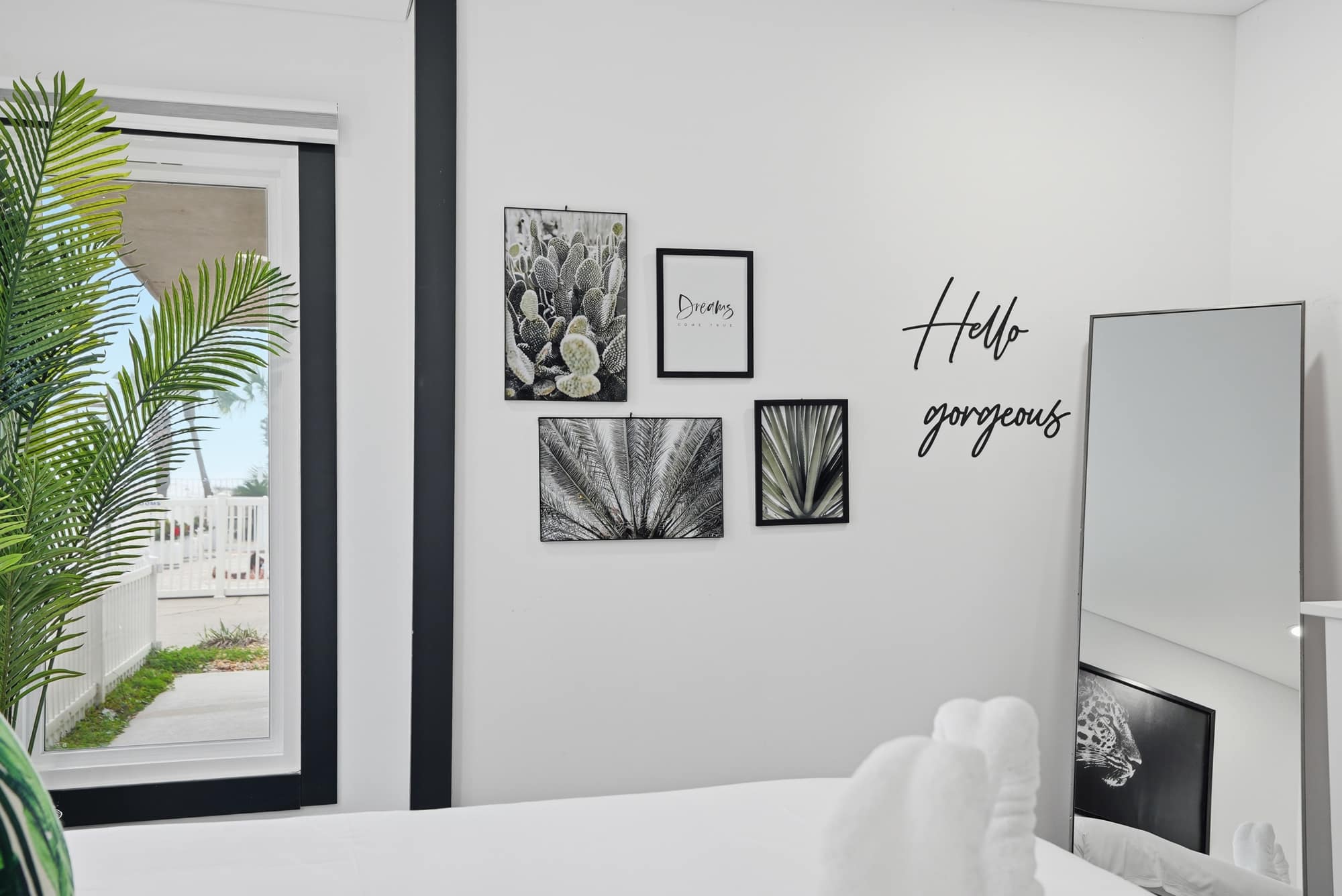 The Summit 132 – Bright room with decorative cactus prints, a large mirror, and a view of outdoor landscaping.