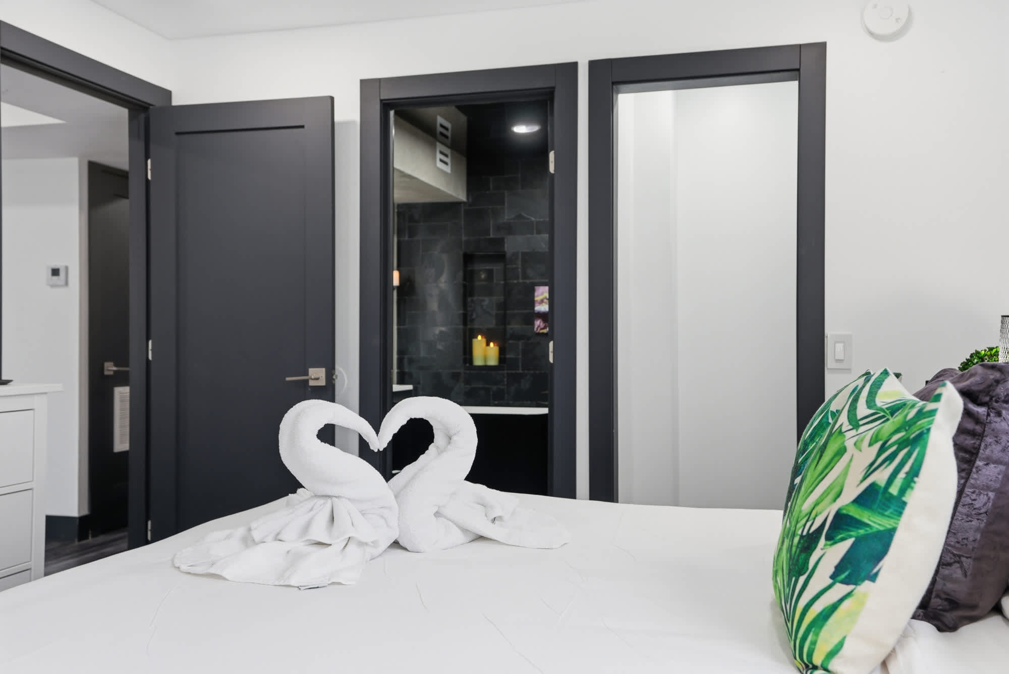 The Summit 132 – Bedroom with towel swans on bed, two doors leading to a bathroom area.