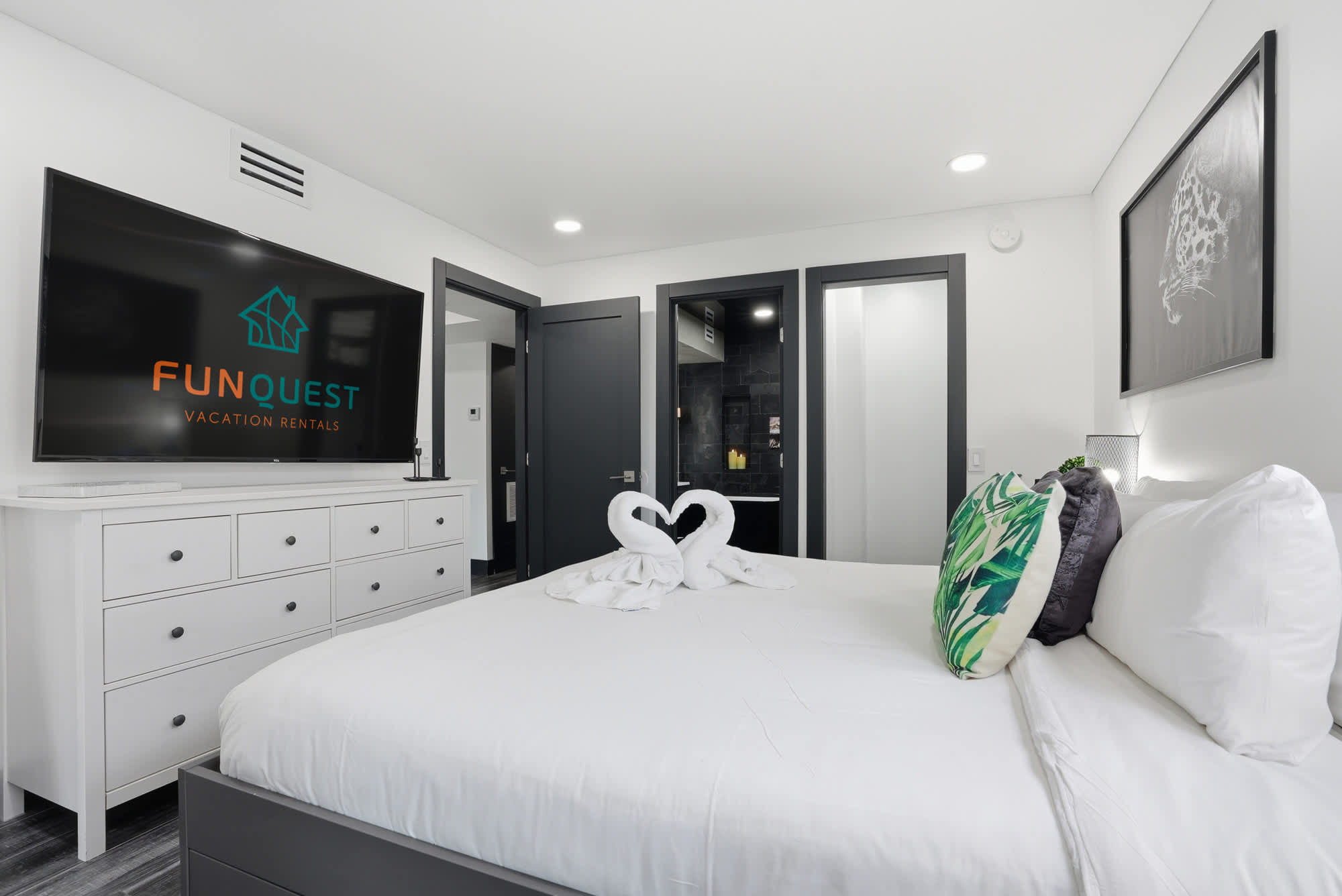 The Summit 132 – Modern bedroom with a king bed, TV, dresser, and decorative towels shaped like swans.