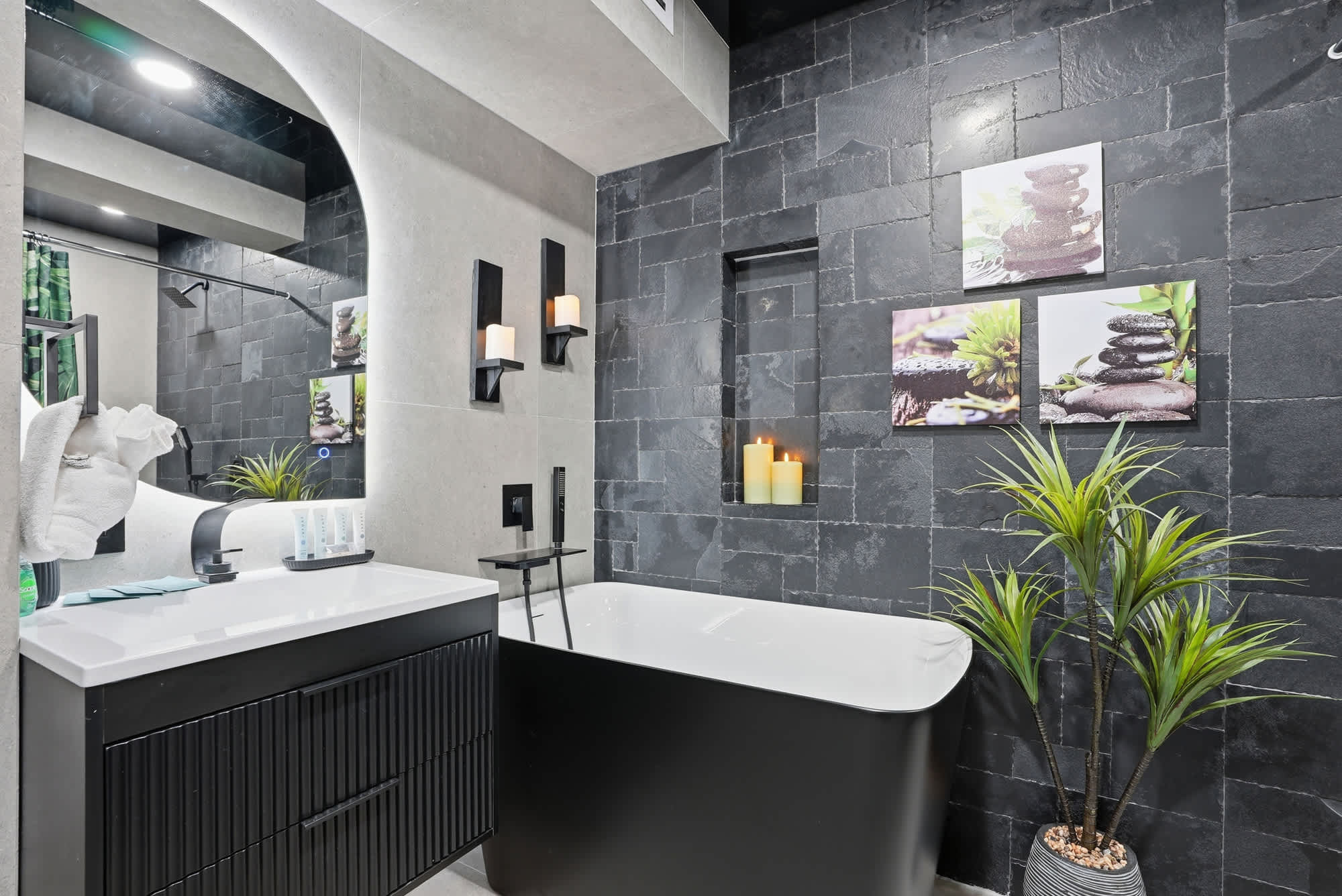The Summit 132 – Modern bathroom featuring a freestanding black tub, vanity, and decorative plants on slate walls.