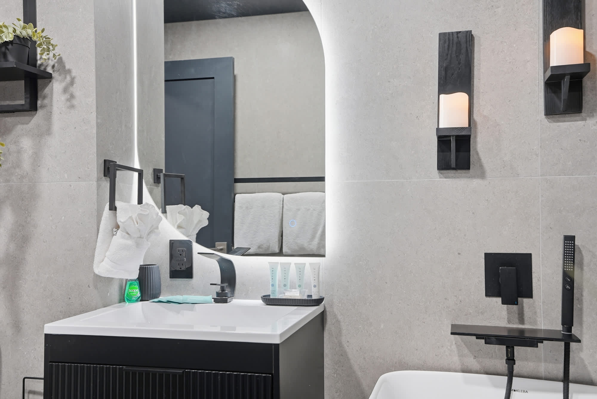 The Summit 132 – Modern bathroom with a sleek vanity, large mirror, and black fixtures, showcasing towels and toiletries.