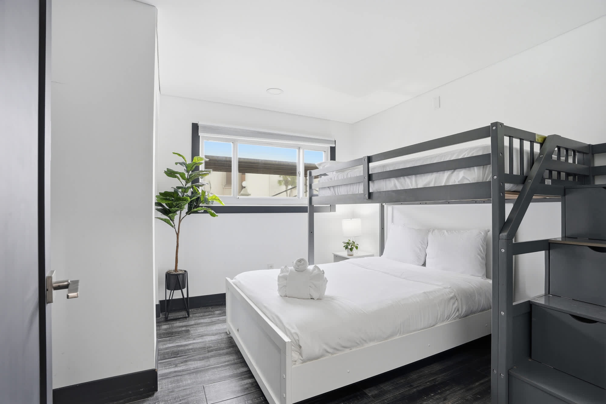 The Summit 132 – Bedroom with a double bed and bunk bed, small window view, and indoor plant in a corner.