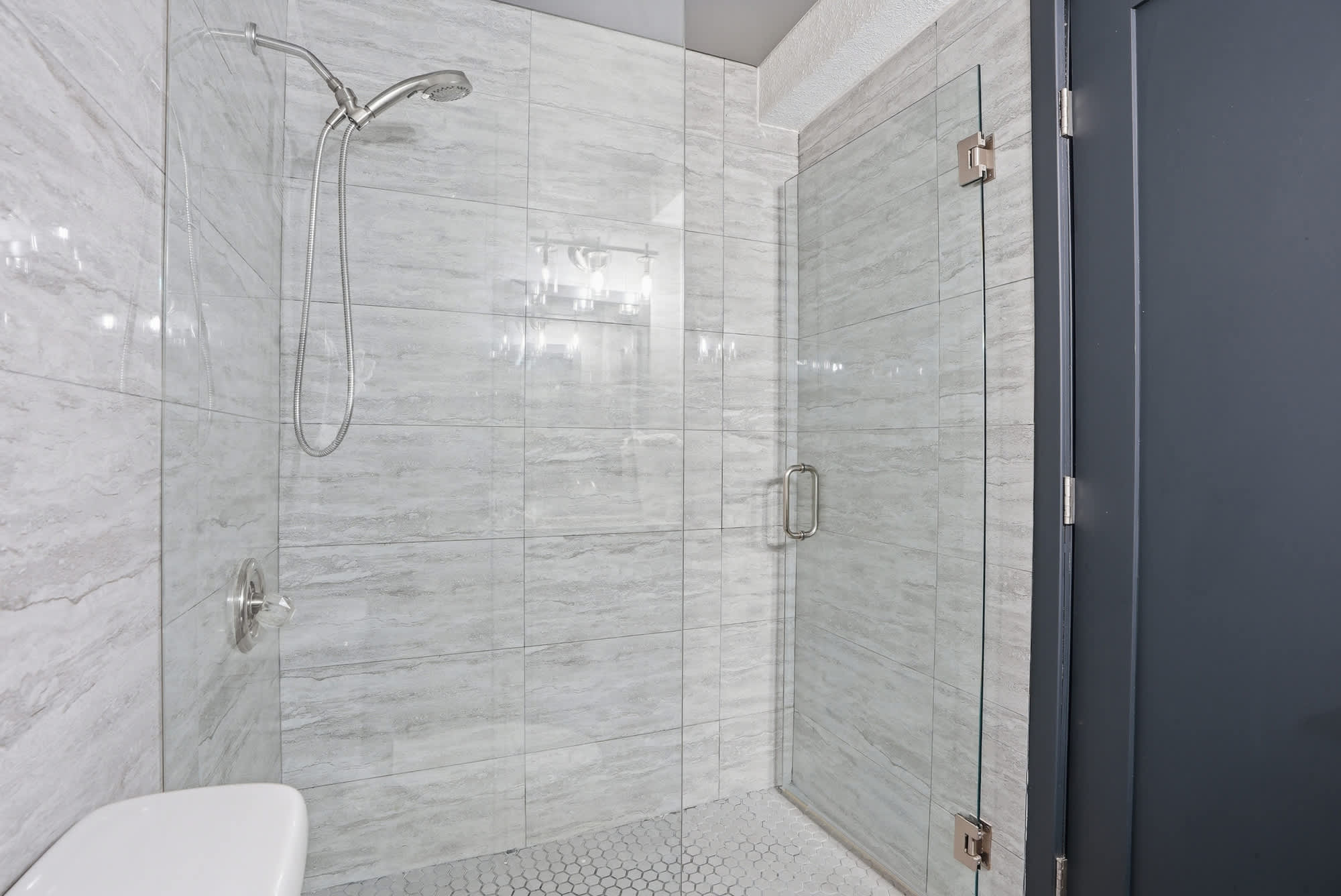 The Summit 132 – Modern bathroom featuring a glass shower enclosure, marble walls, and a hexagon tile floor.