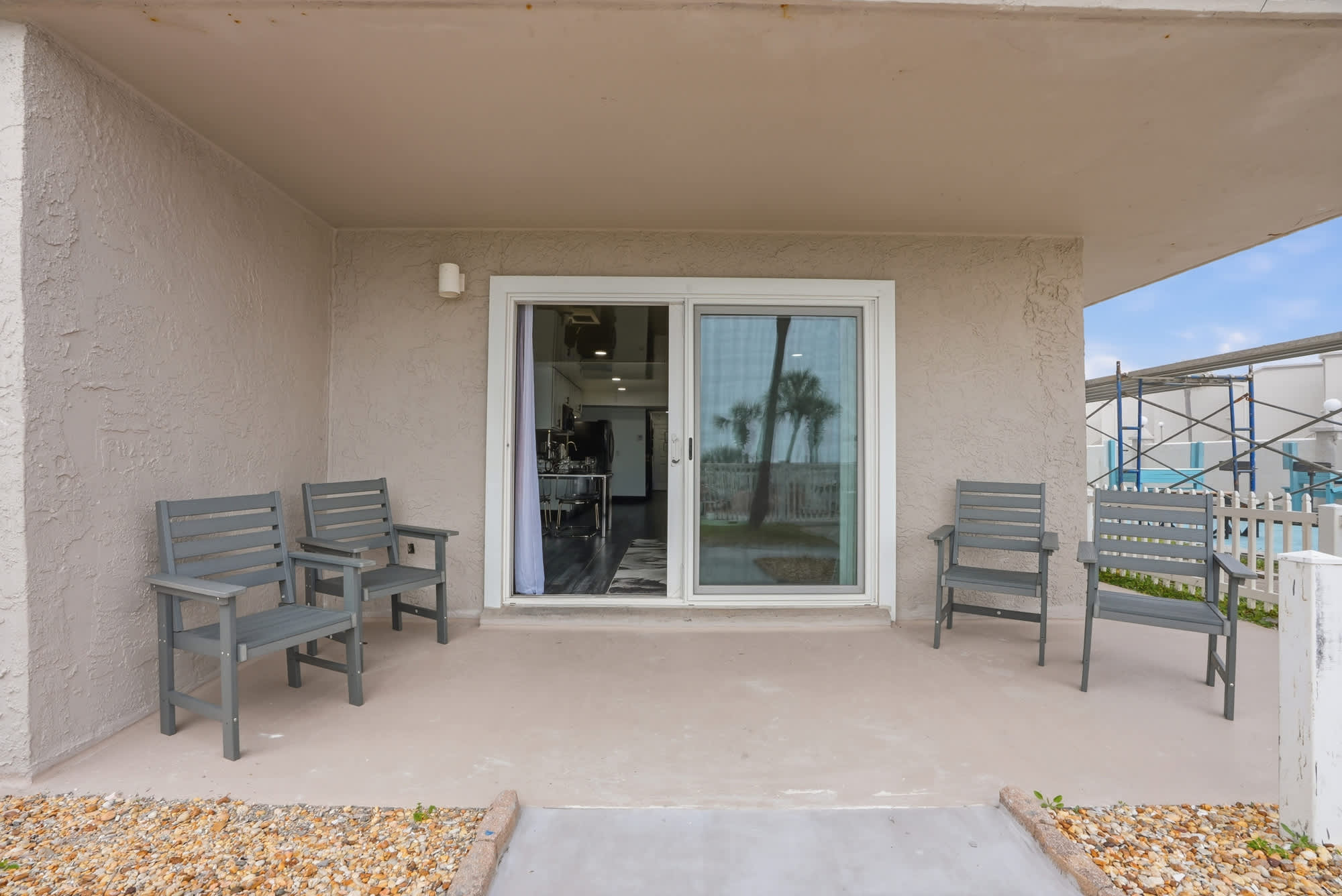The Summit 132 – Patio with four gray chairs and sliding glass door leading to interior space.