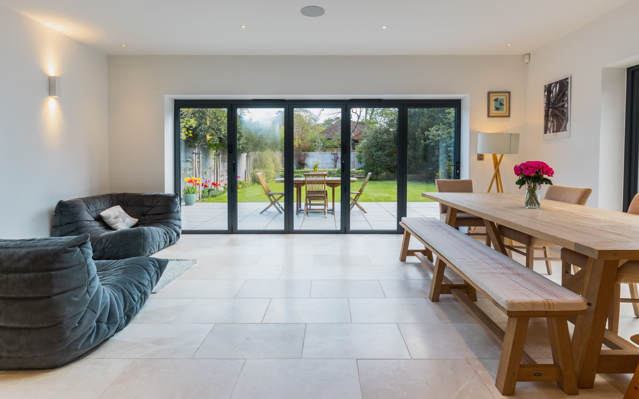 Open-plan dining and lounge with garden views and large bi-fold doors for seamless indoor-outdoor living.