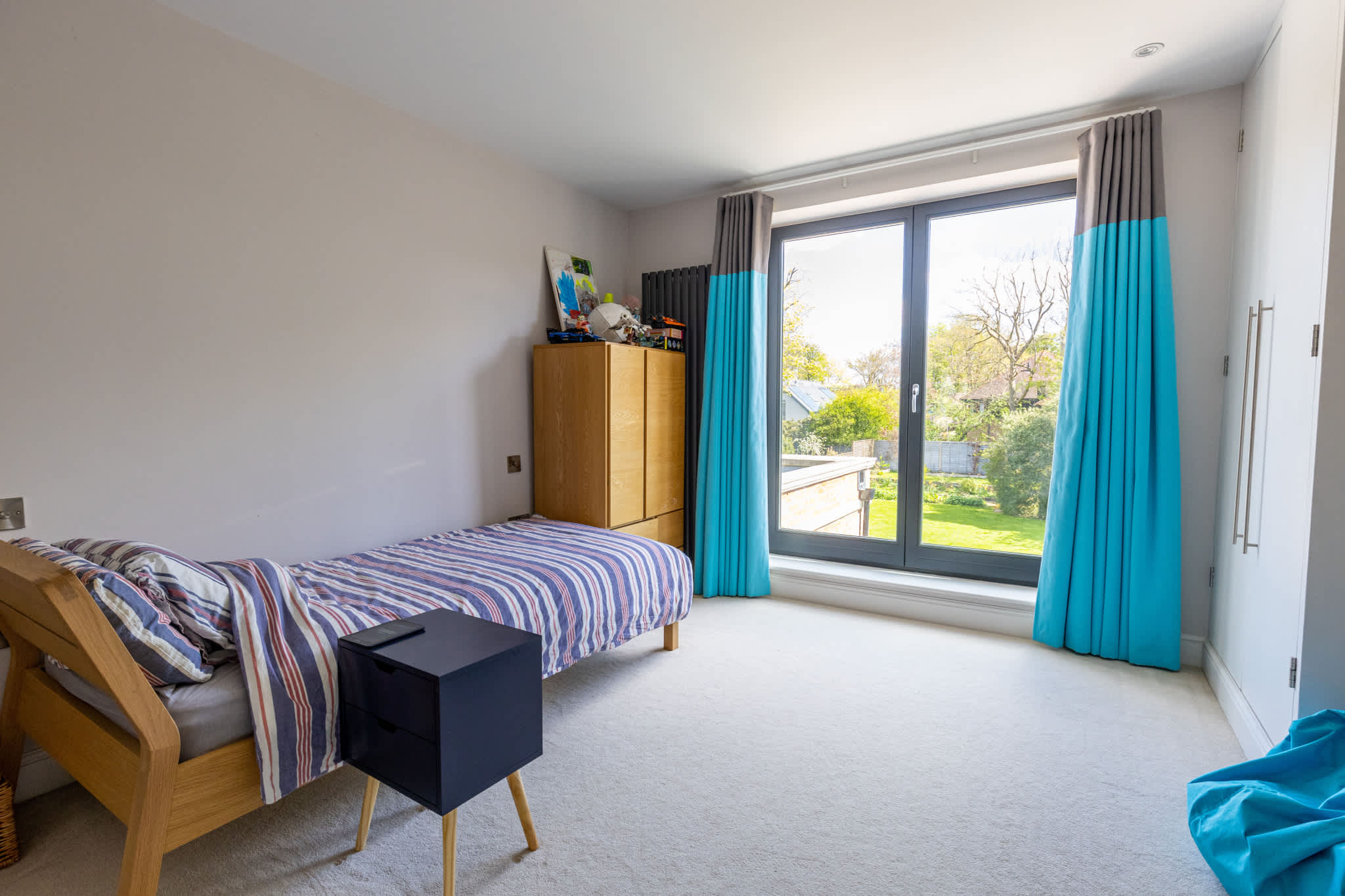Bright bedroom with garden views and large window, offering a calm and comfortable space.