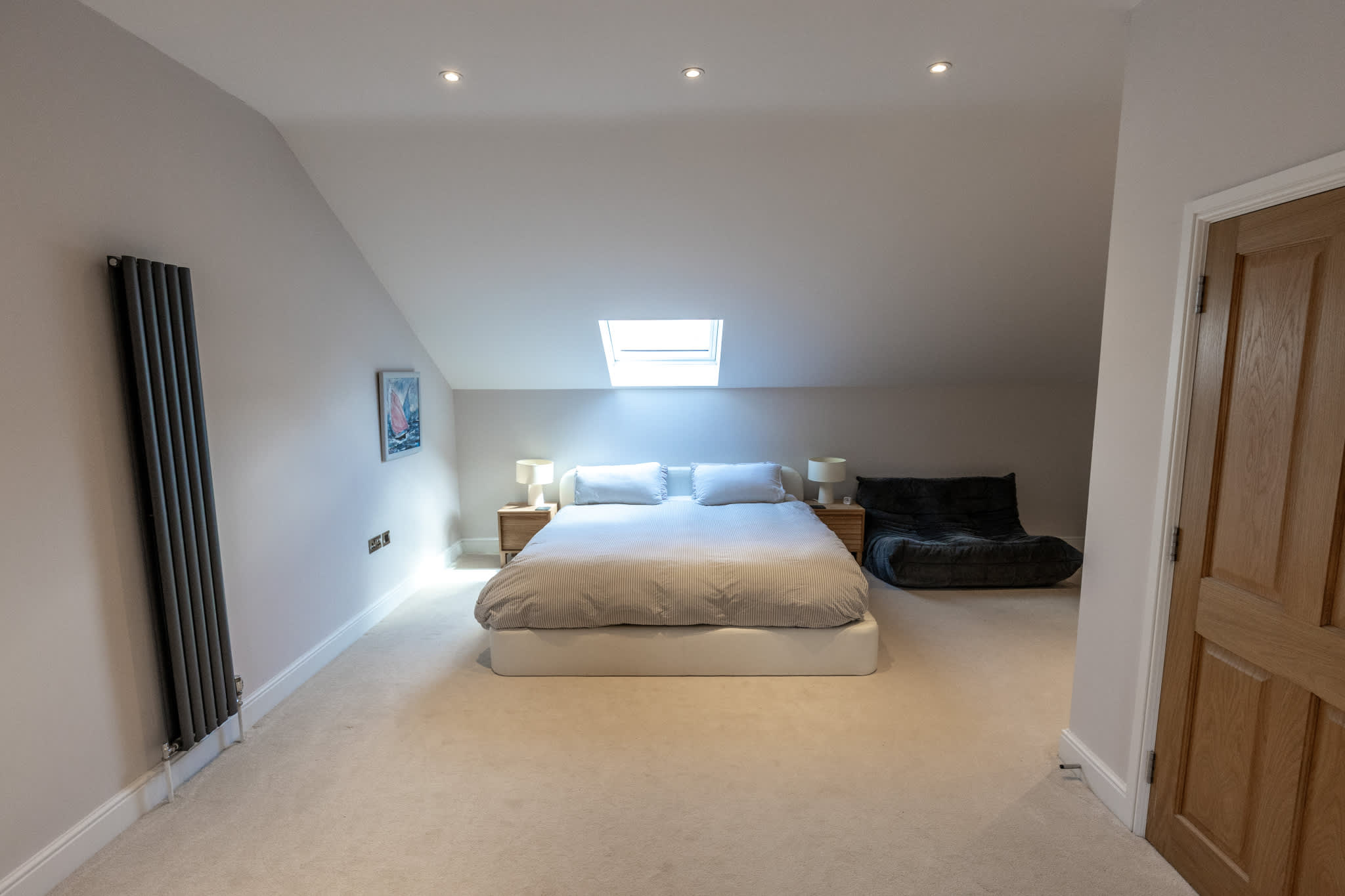 Spacious loft bedroom with skylight, king bed and cosy seating area.