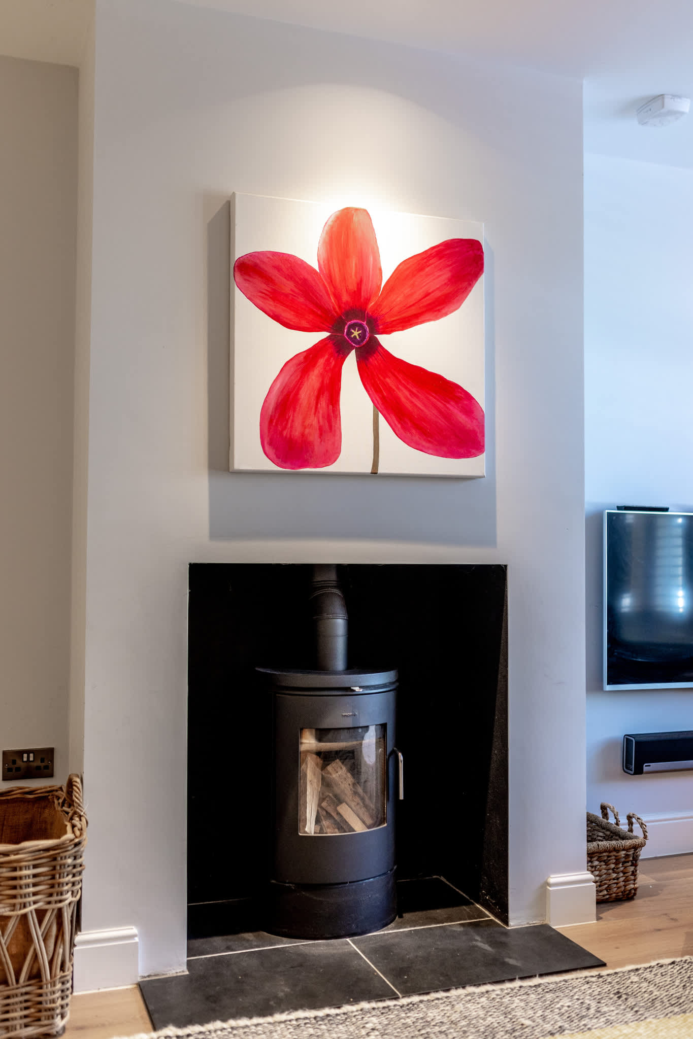 Stylish log burner with modern fireplace and statement artwork, creating a cosy focal point in the lounge.
