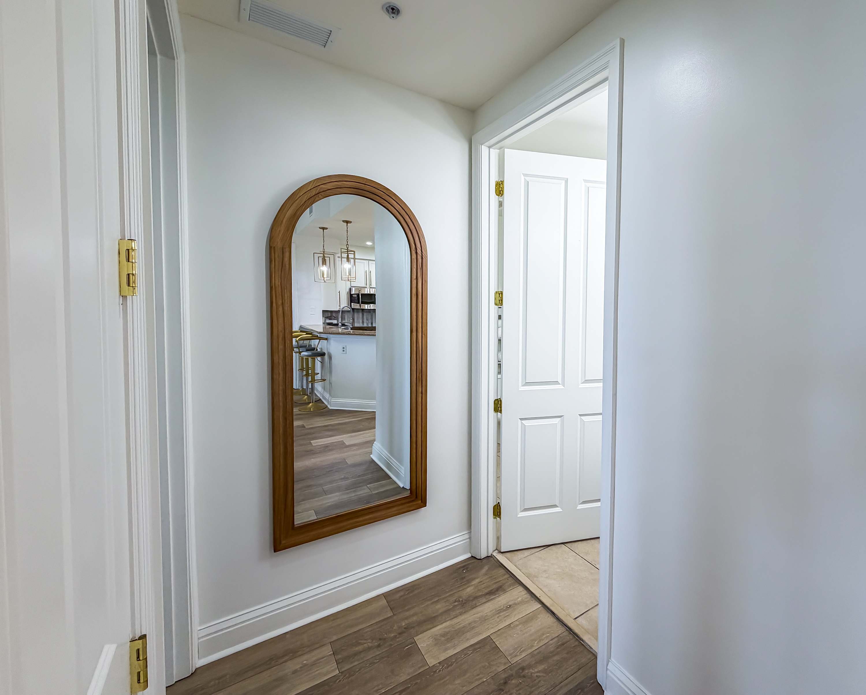 Marriott 3707 – Interior hallway with a large arched mirror and doorway leading to a kitchen area.