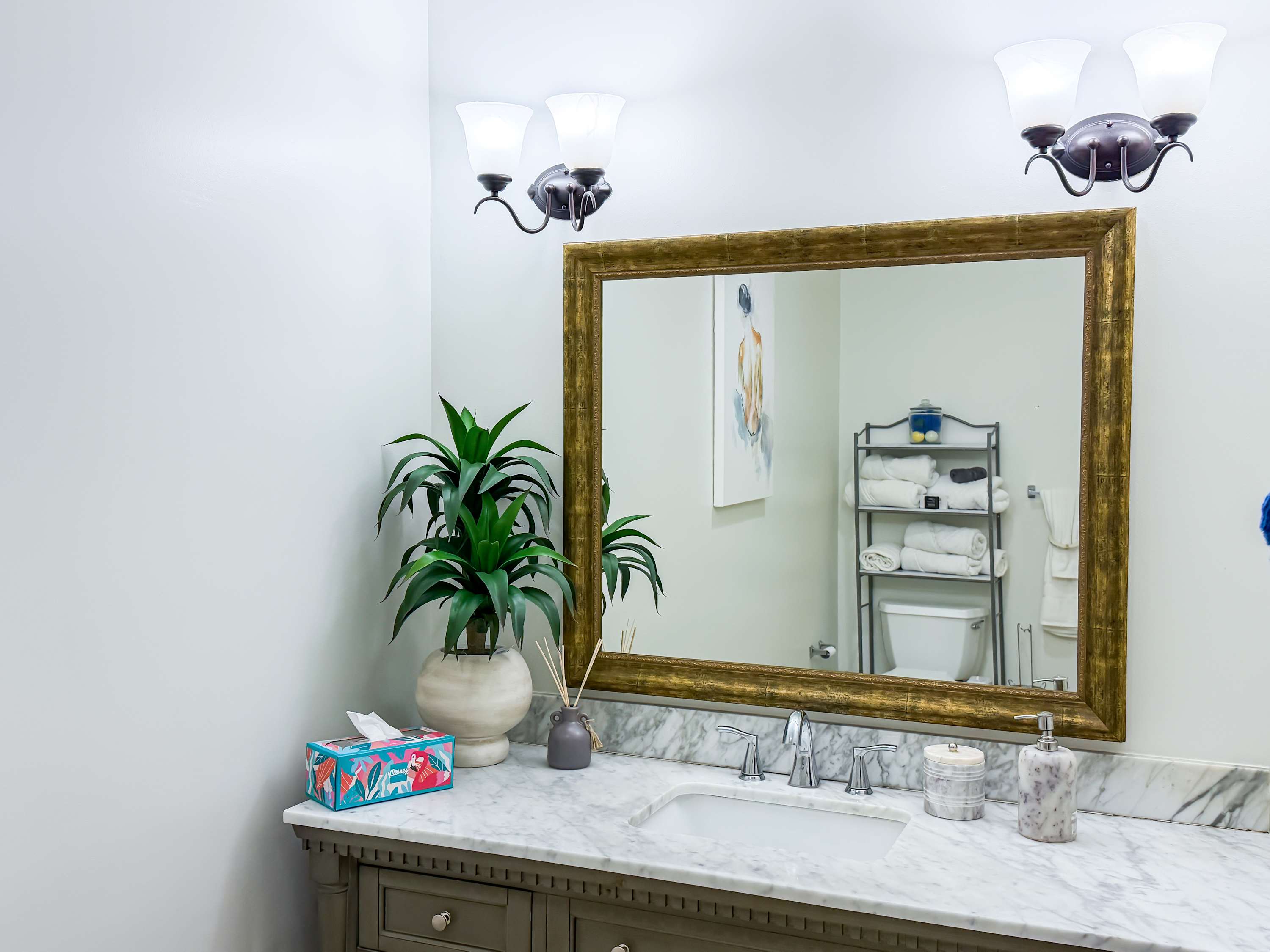 Marriott 3707 – Bathroom with marble countertop, framed mirror, potted plant, and towels on a rack in the background.