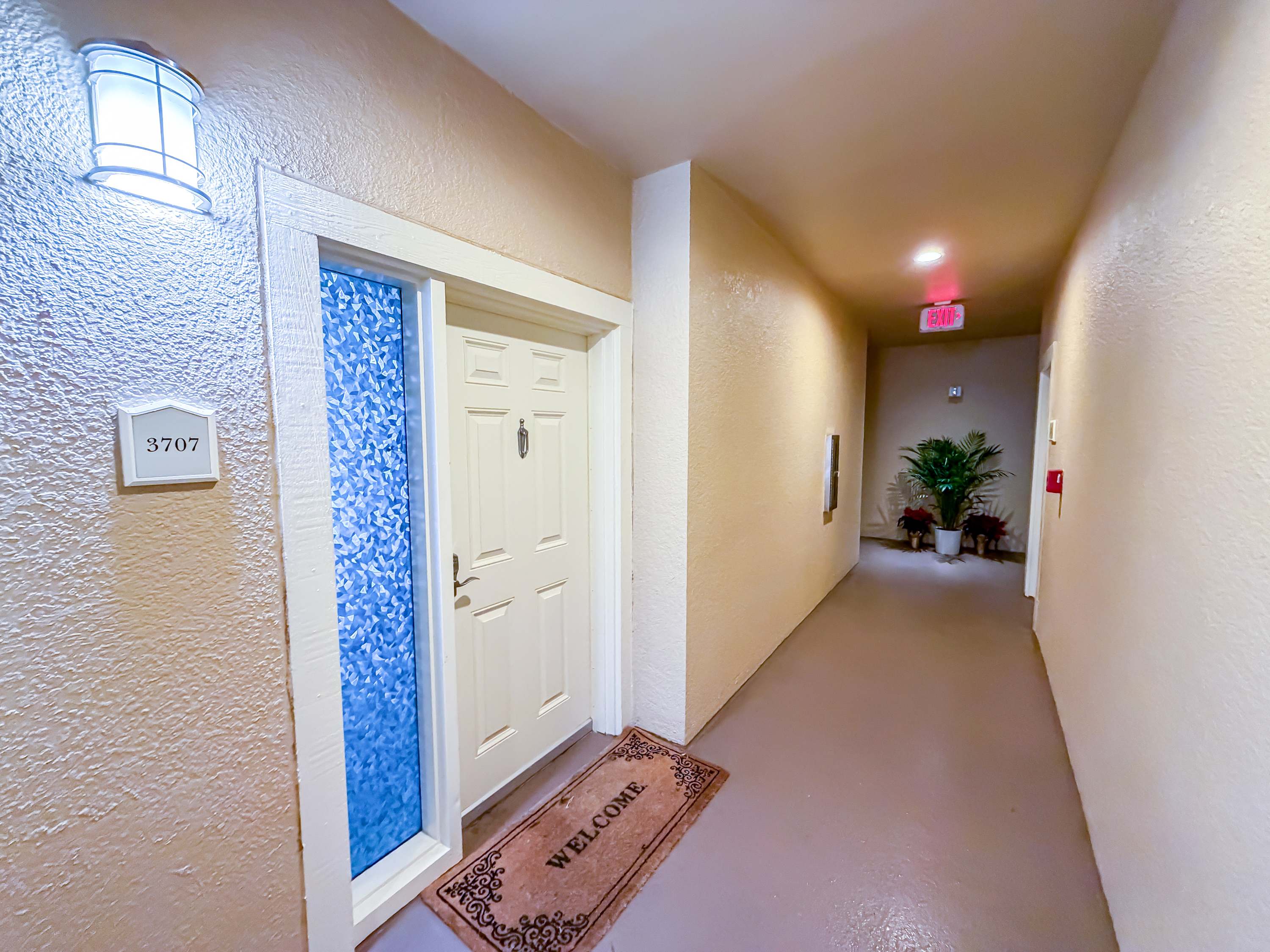 Marriott 3707 – Hallway leading to door 3707, featuring a welcome mat and decorative plants.