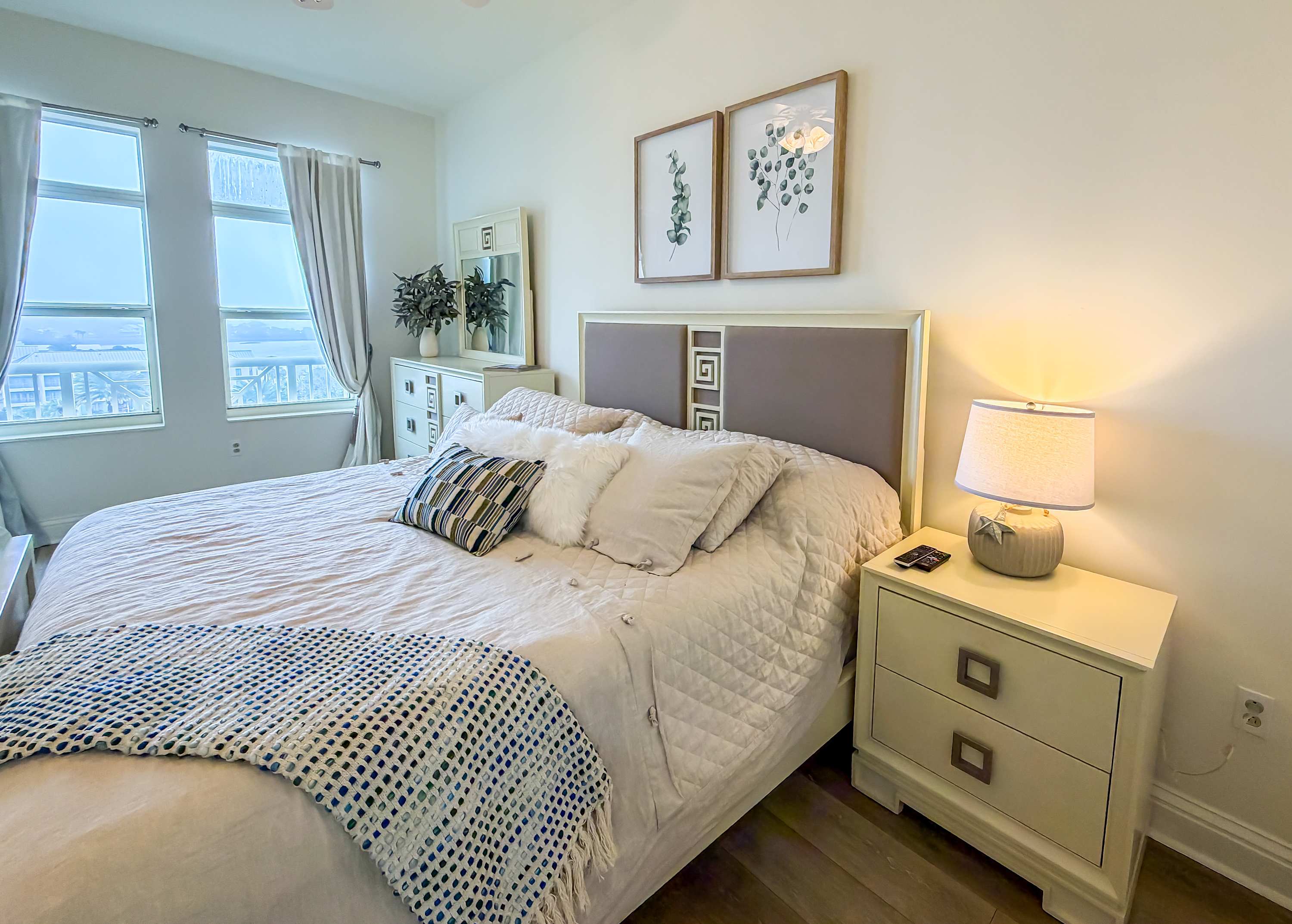 Marriott 3707 – Bright bedroom featuring a queen bed, large windows, dresser, and nightstand with a lamp.