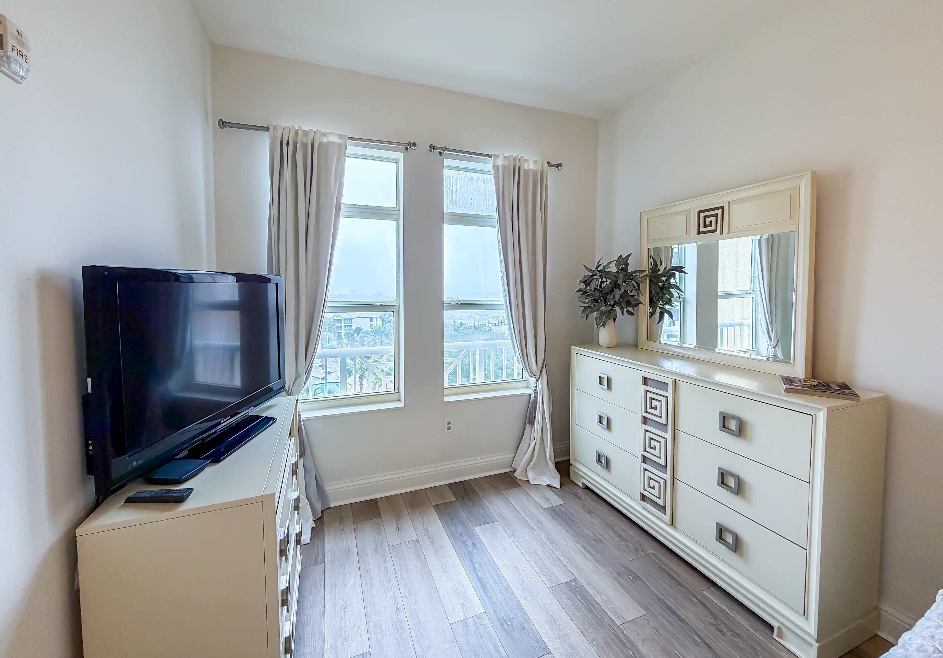 Marriott 3707 – Bright room with a TV, dresser, and windows offering a view of palm trees.