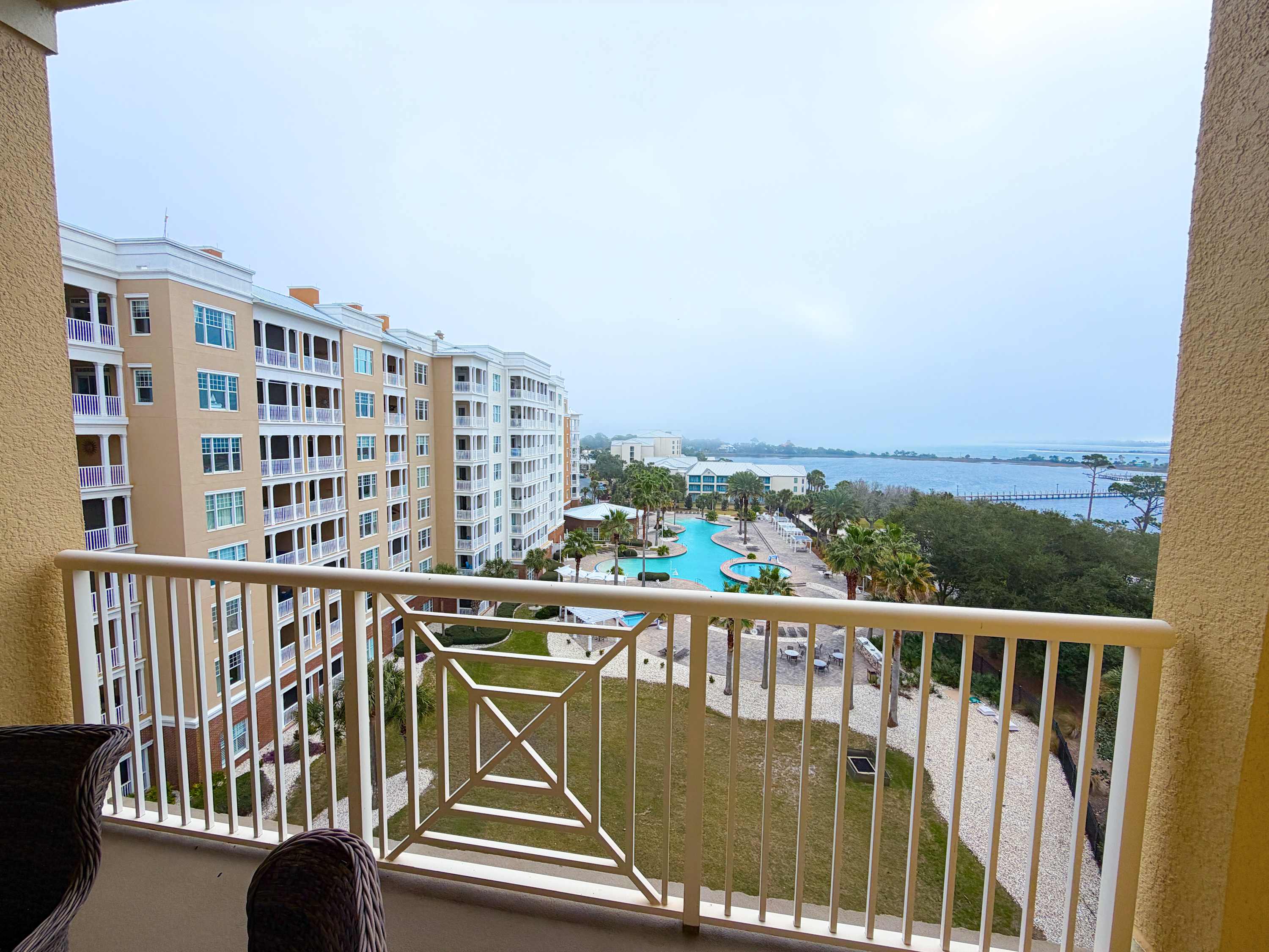 Marriott 3707 – Balcony view of a pool and surrounding buildings, with distant water and palm trees visible.