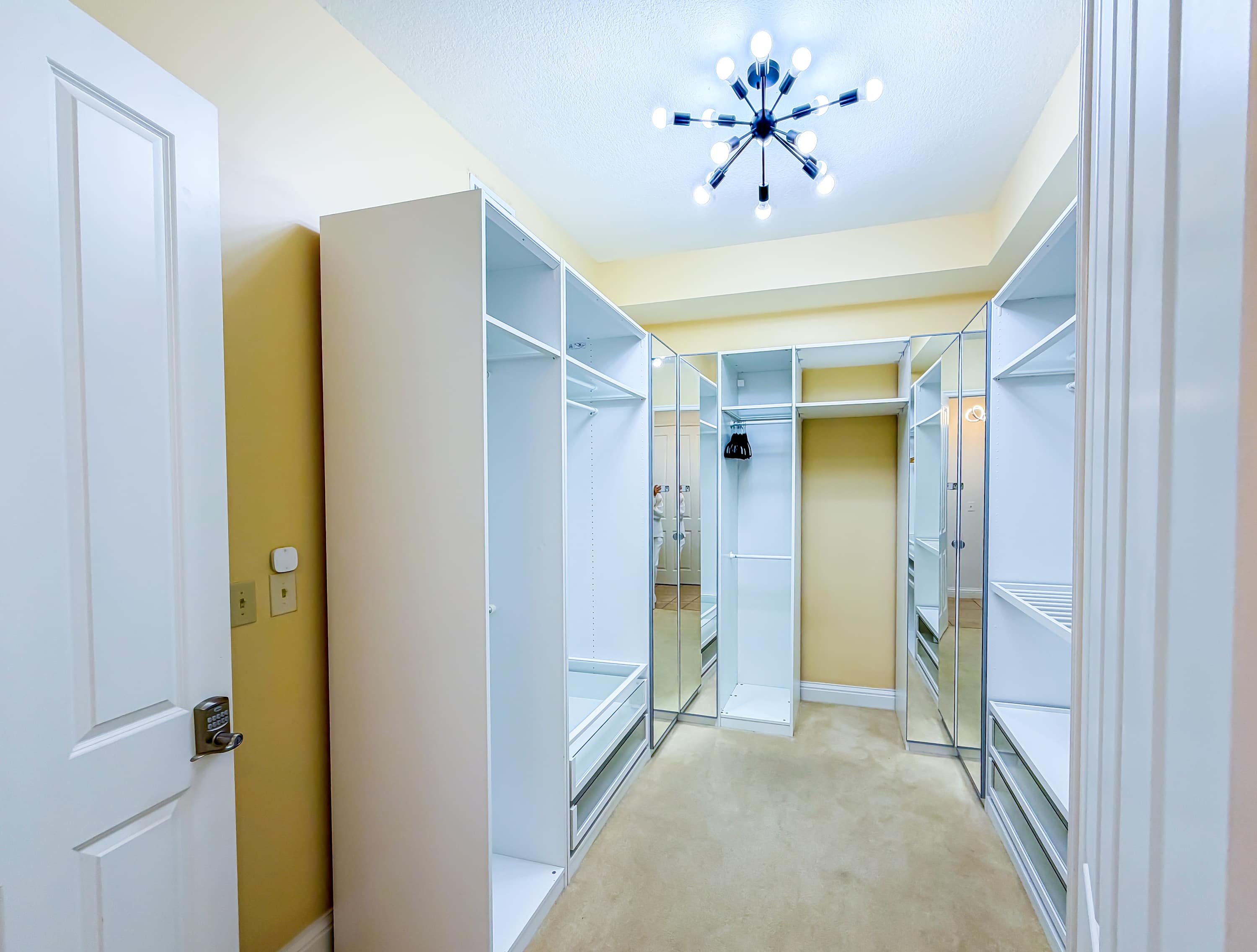 Marriott 3707 – Walk-in closet with mirrored doors, built-in shelves, beige carpet, and modern ceiling light fixture.