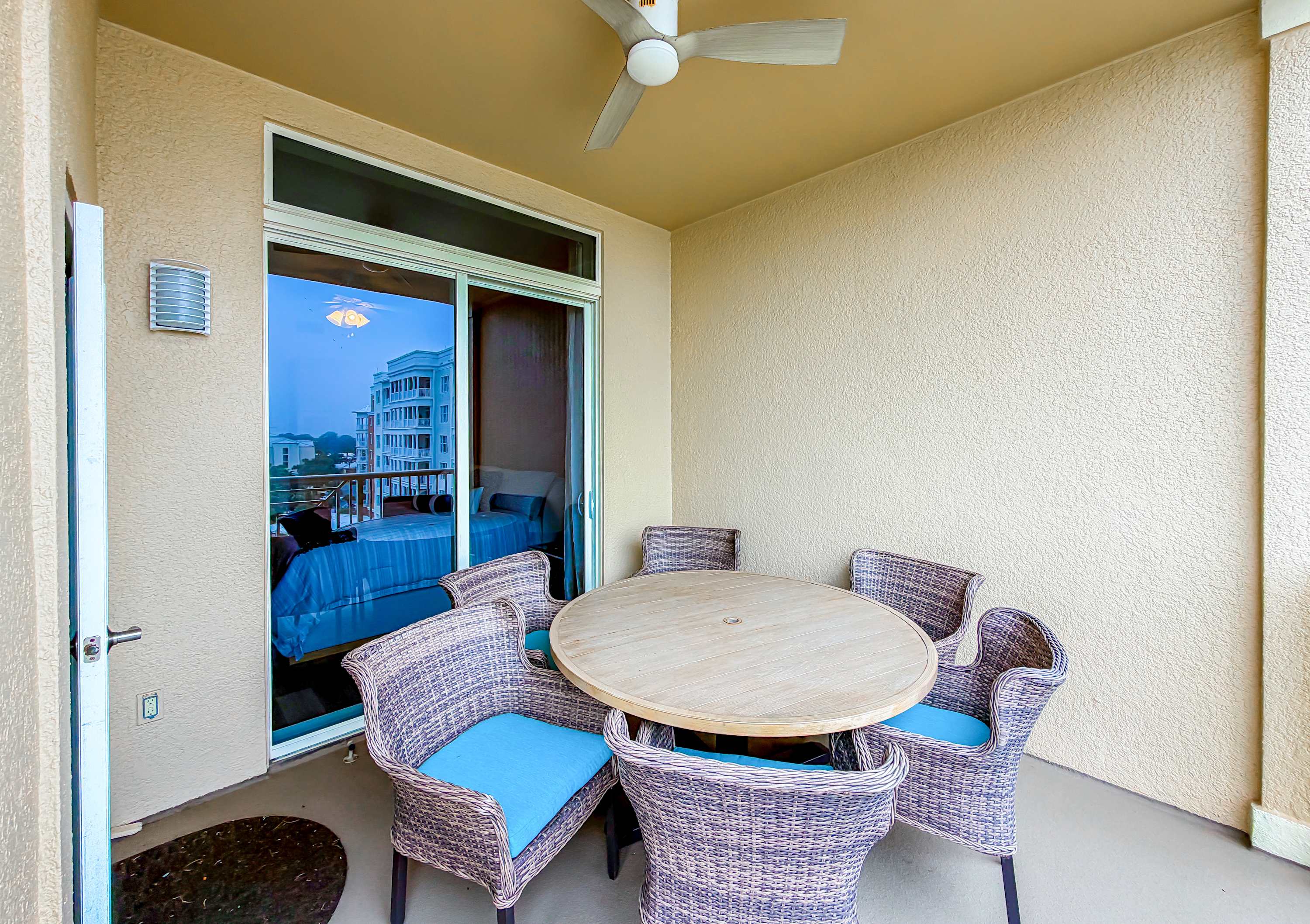 Marriott 3707 – Patio with a round table and six wicker chairs, ceiling fan, and view of nearby buildings.