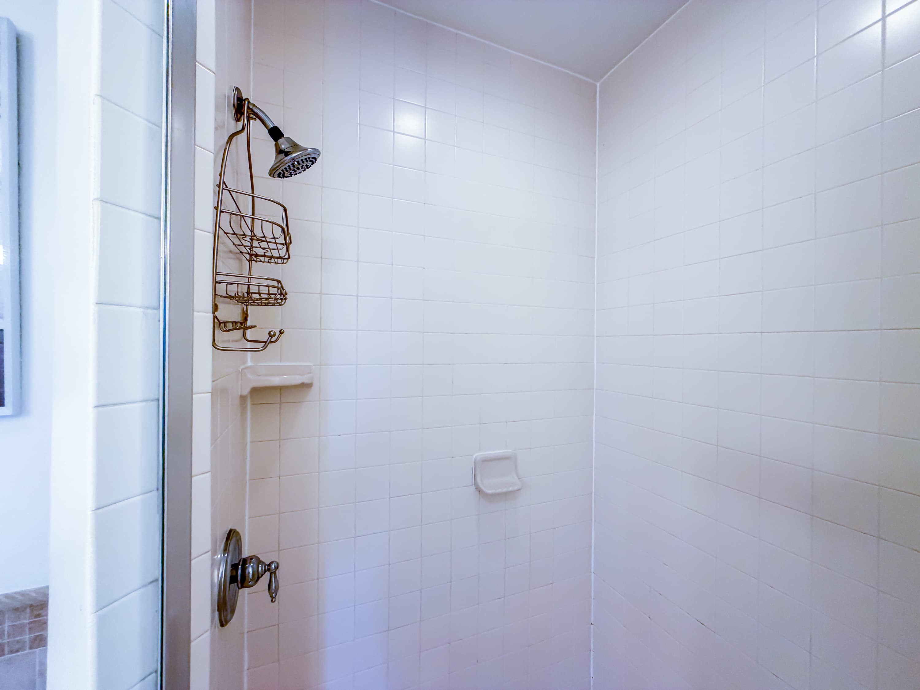 Marriott 3707 – Shower stall with tiled walls, handheld showerhead, and wire shelf storage.