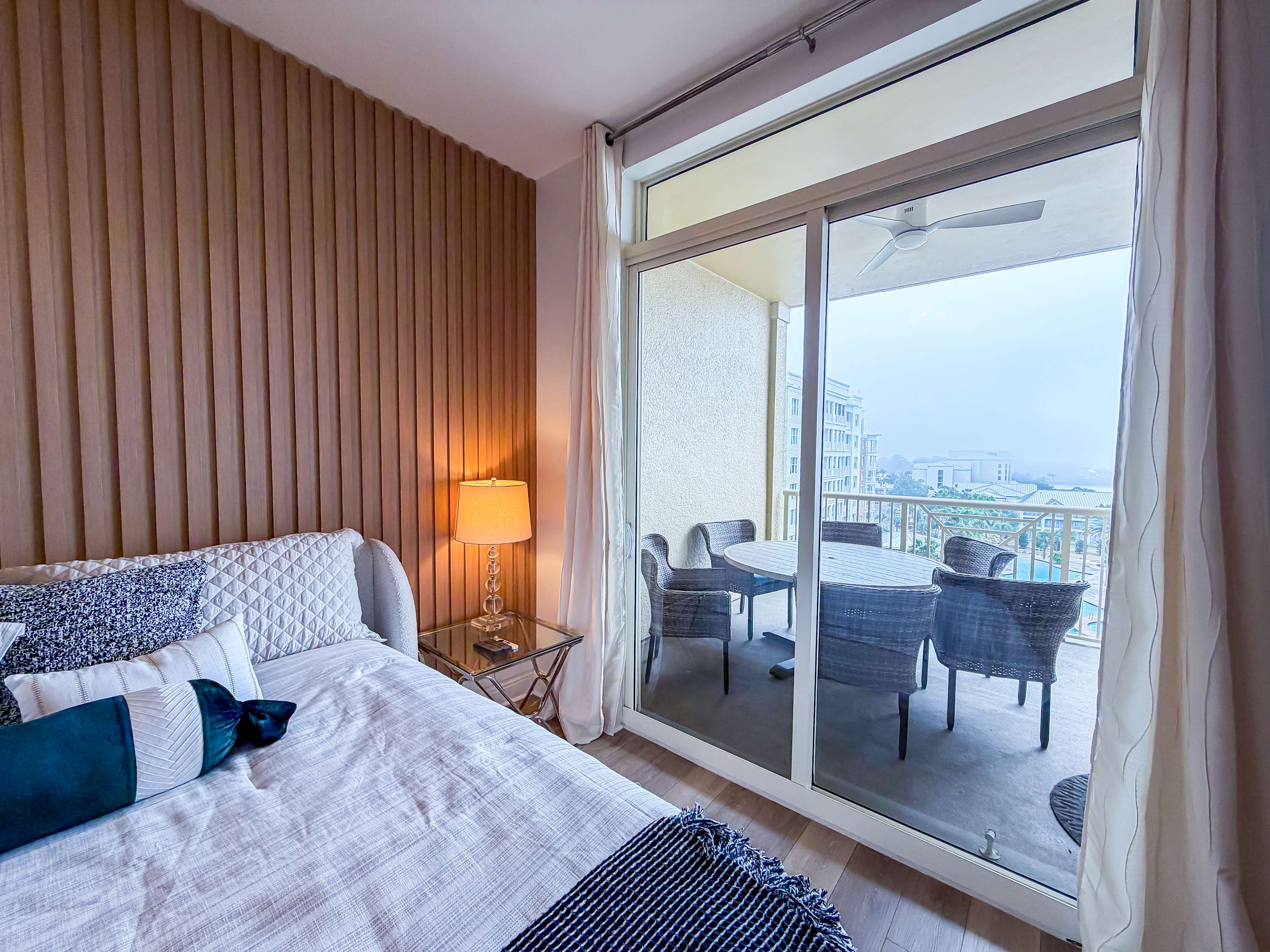 Marriott 3707 – Bedroom with a bed, lamp, and sliding doors to a balcony with outdoor seating.