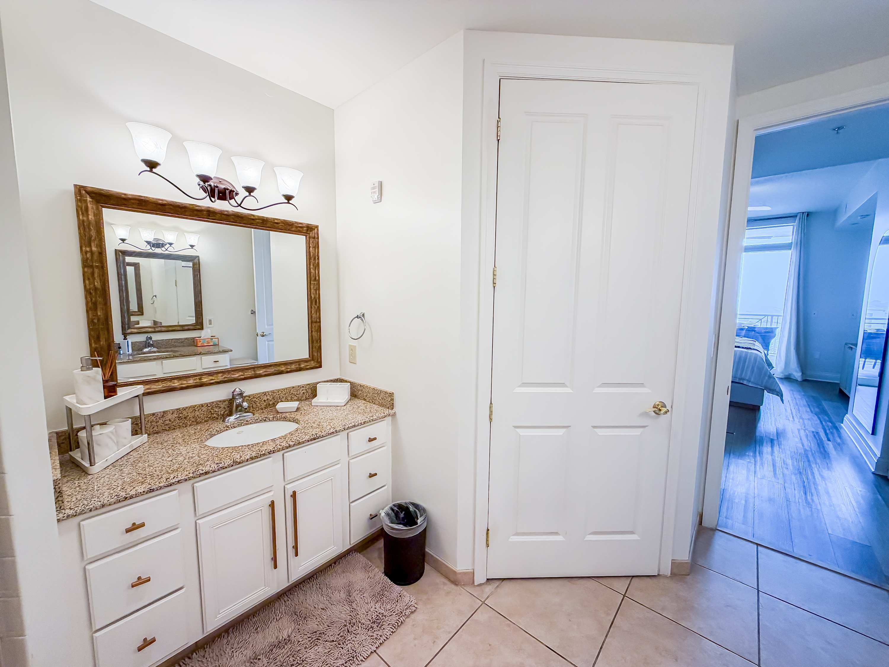 Marriott 3707 – Bathroom with a double sink vanity, large mirror, and door leading to a bedroom with a view.