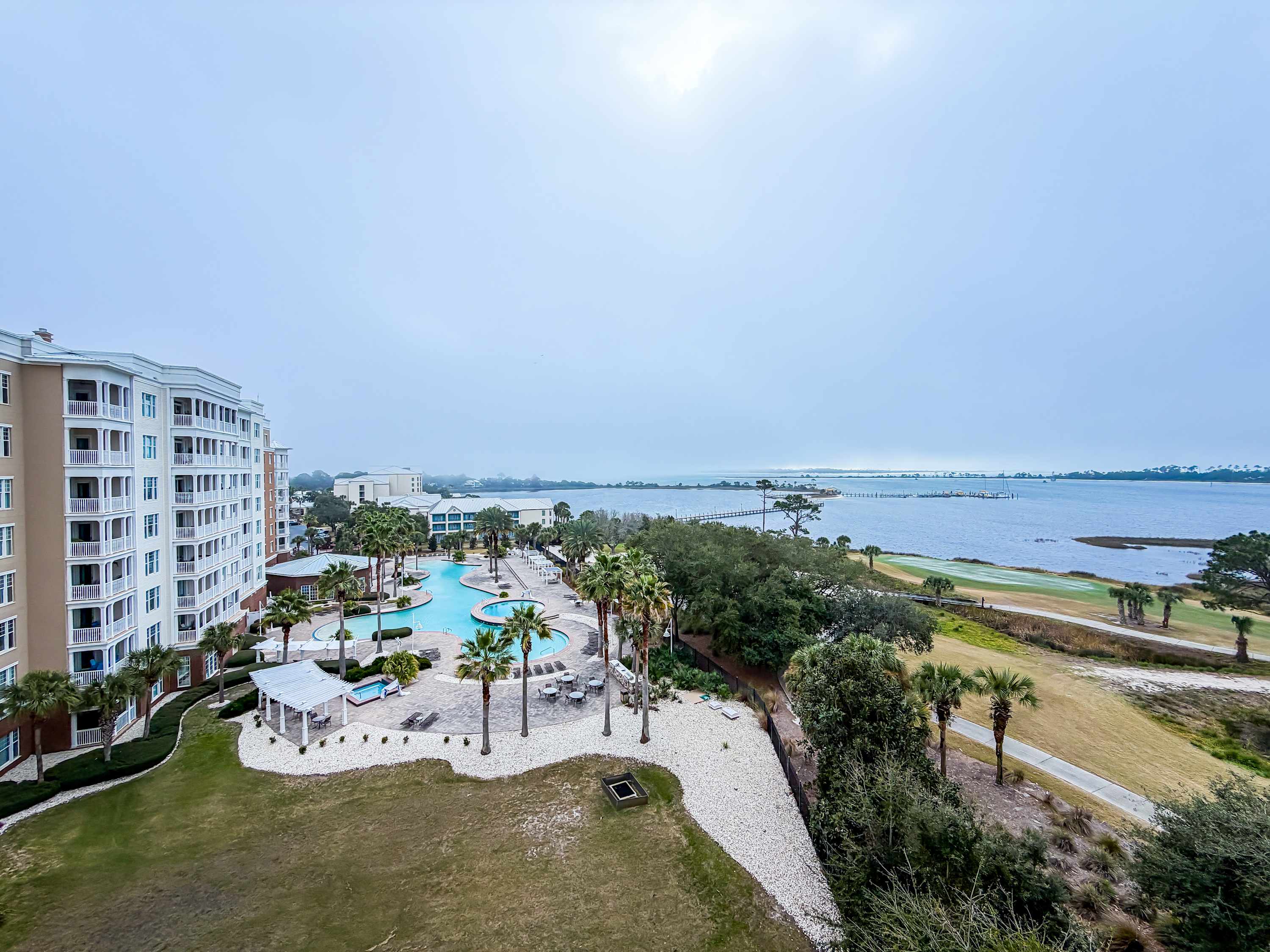 Marriott 3707 – View of a waterfront pool area and palm trees beside a bay and distant shoreline.
