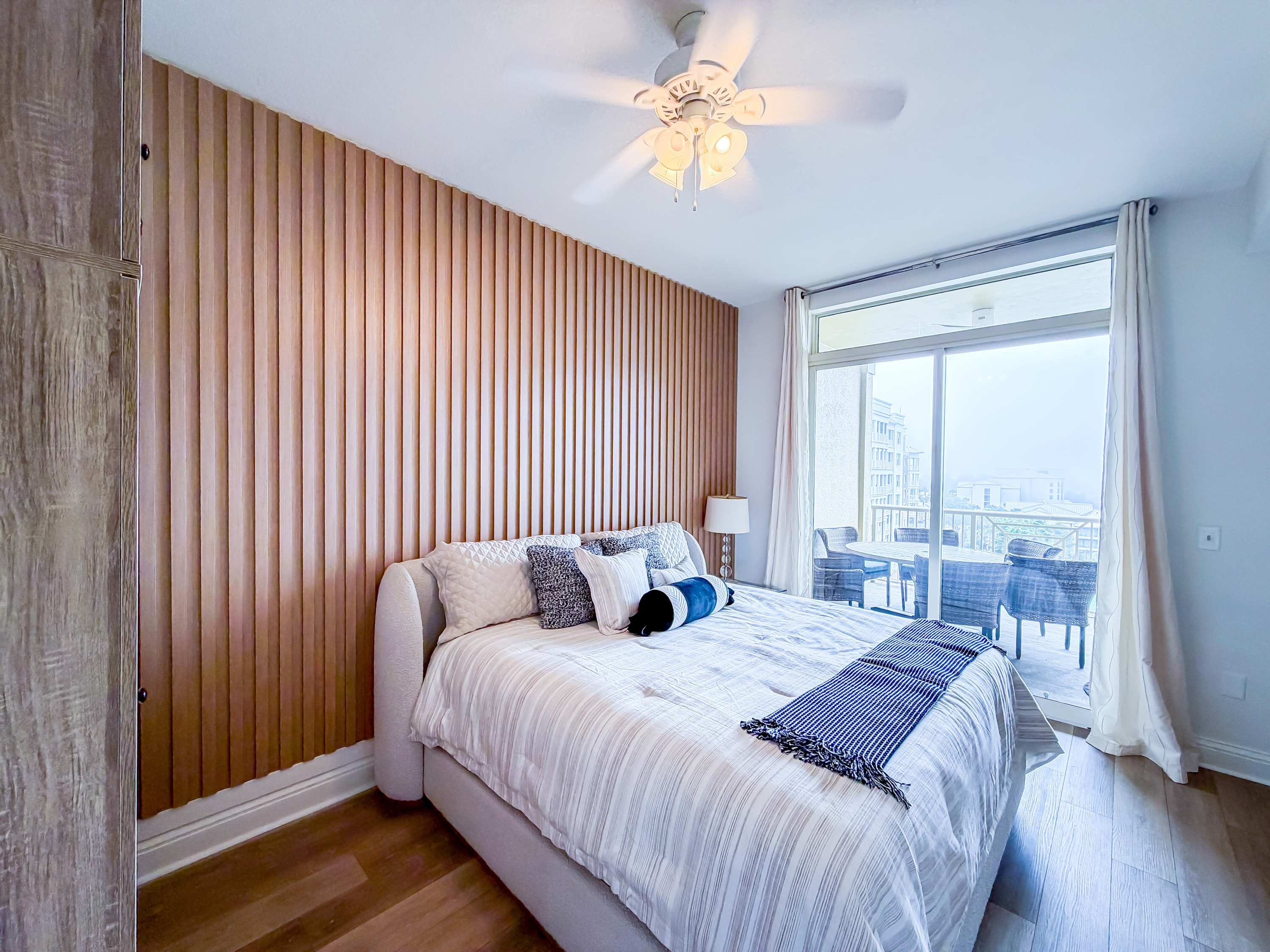Marriott 3707 – Cozy bedroom with a striped bedspread, wooden accent wall, and glass doors opening to a balcony.