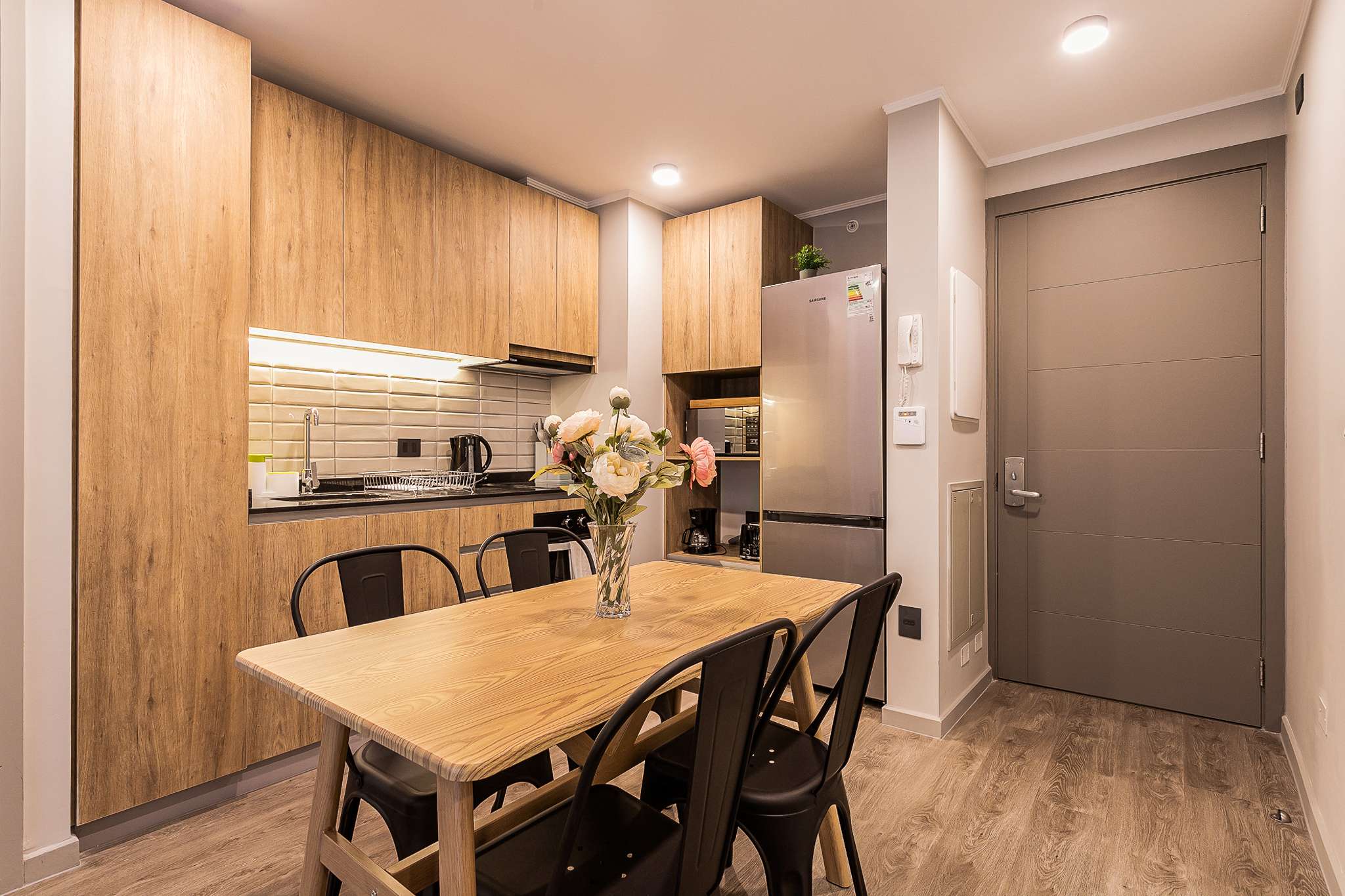 Private kitchen with warm wood cabinetry, a full set of appliances, and a dining table for shared meals.