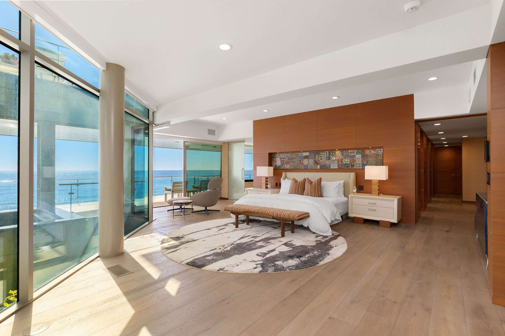 Oceanfront bedroom suite framed by floor-to-ceiling glass and Pacific views.