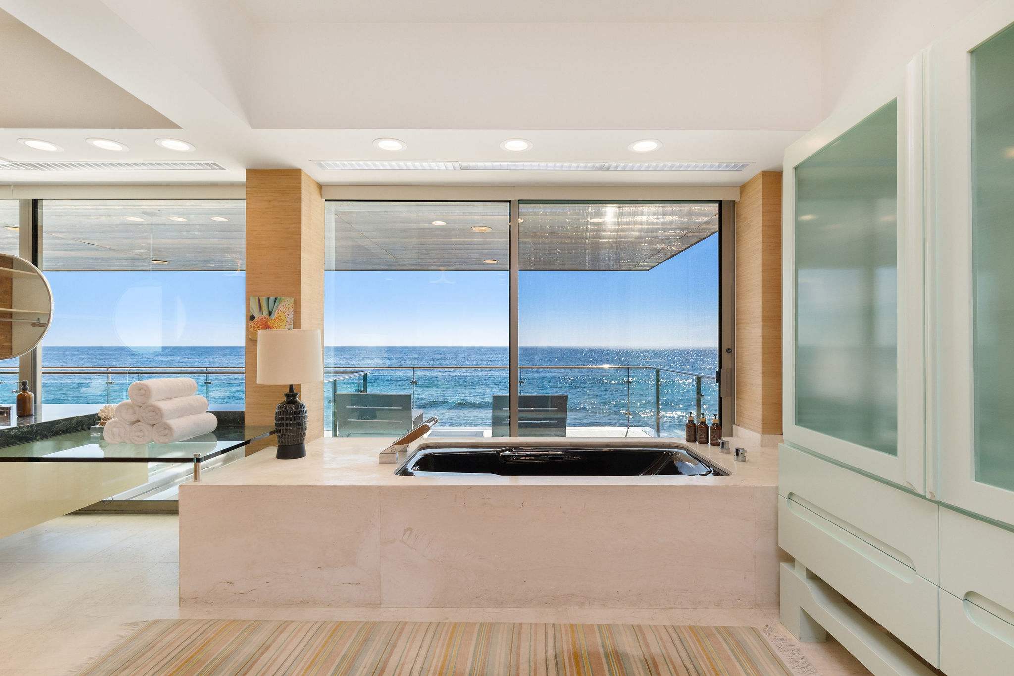 Freestanding soaking tub positioned beside floor-to-ceiling glass in a Malibu luxury bath.