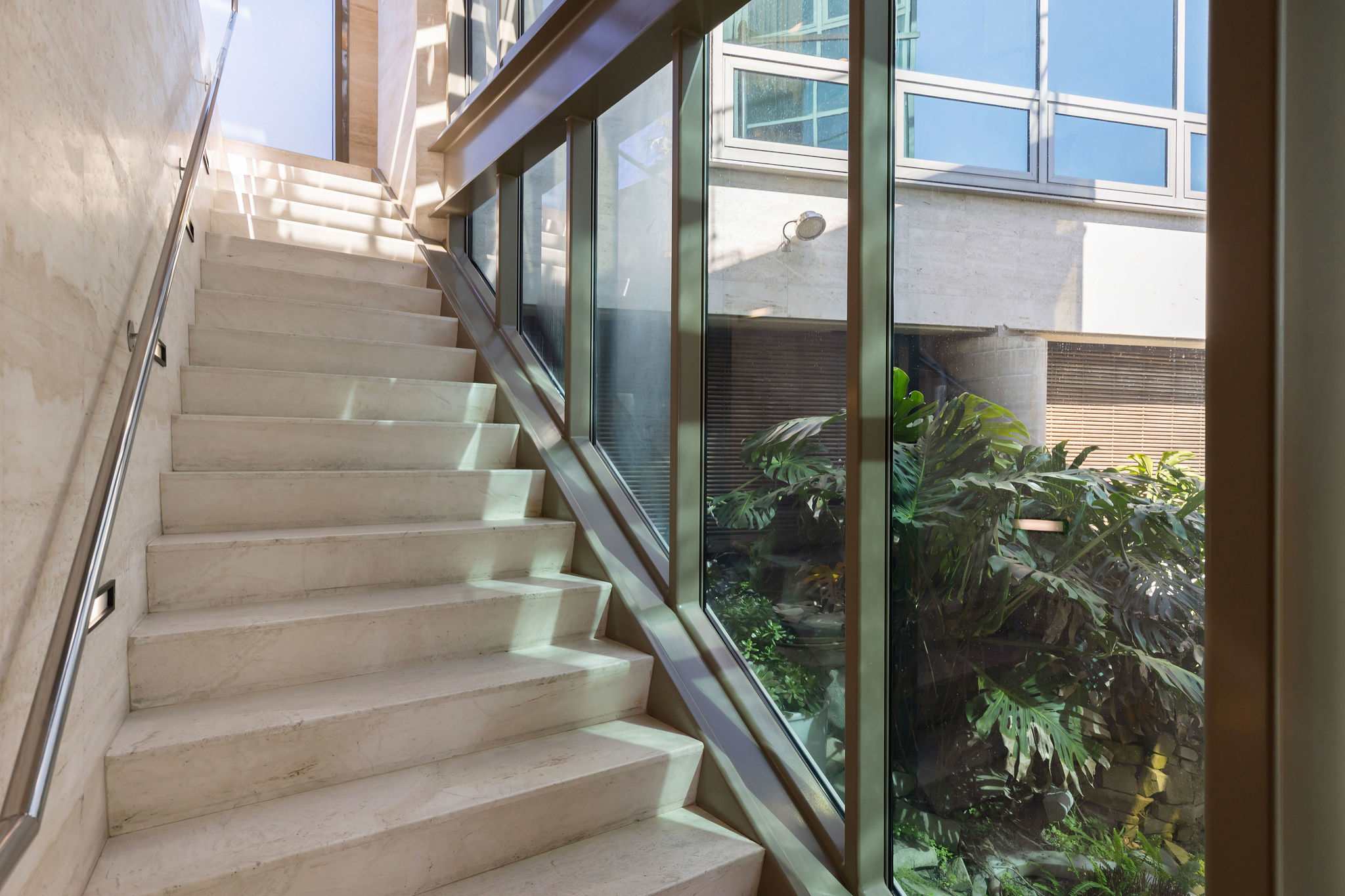 Sculptural staircase framed by glass architecture.