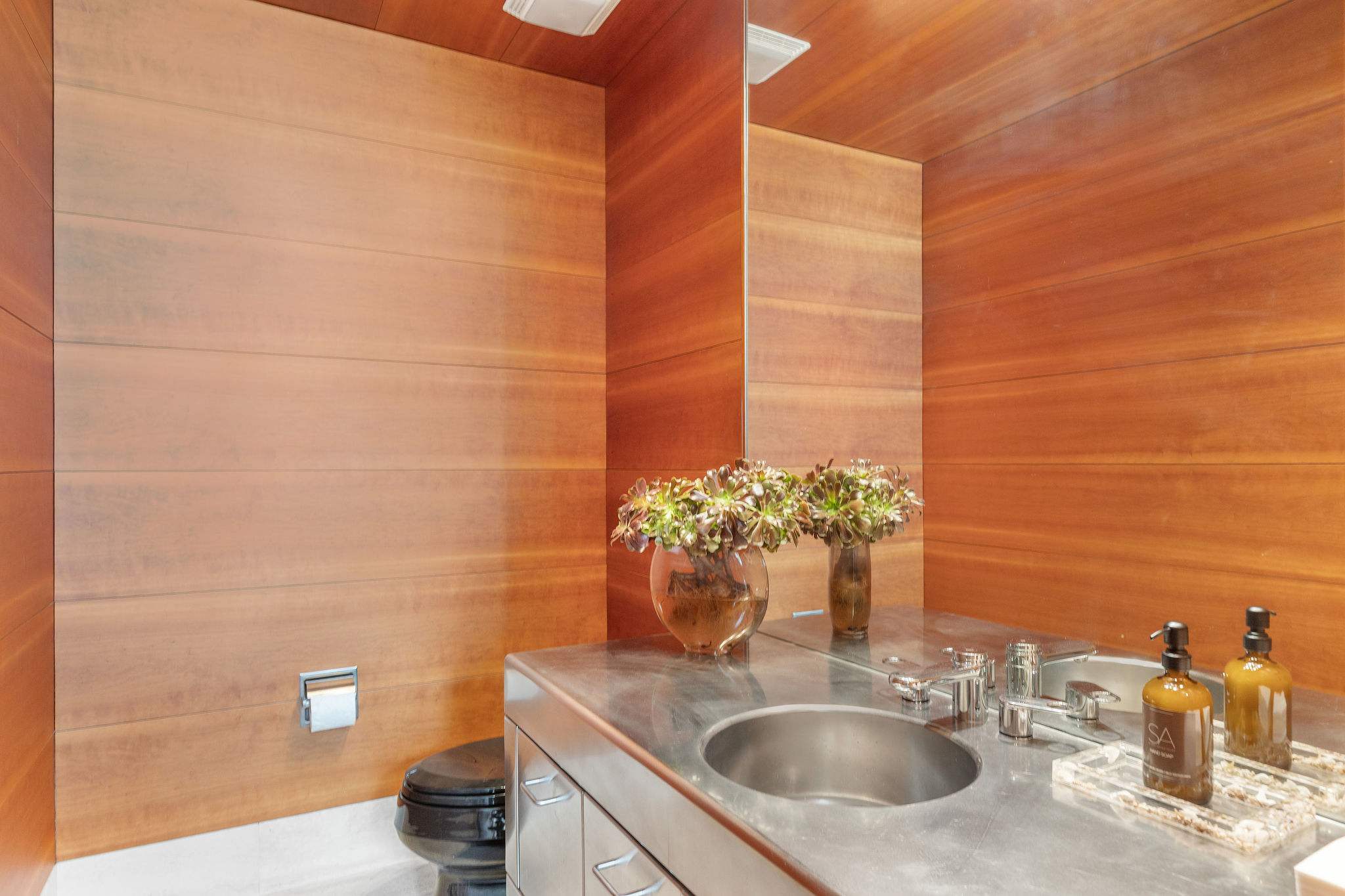 Designer powder room with stone basin and warm wood finishes.