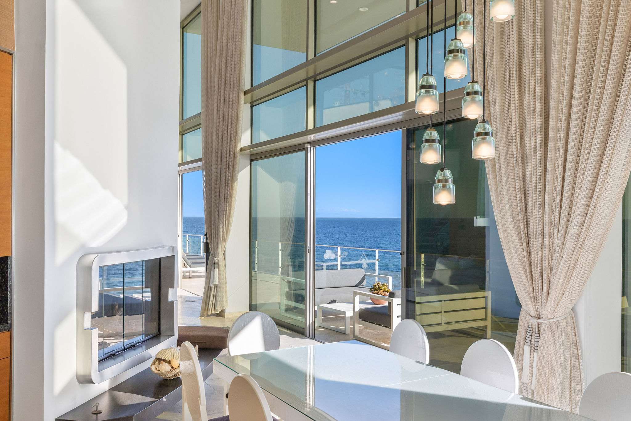 Malibu dining area framed by expansive glass and Pacific views.